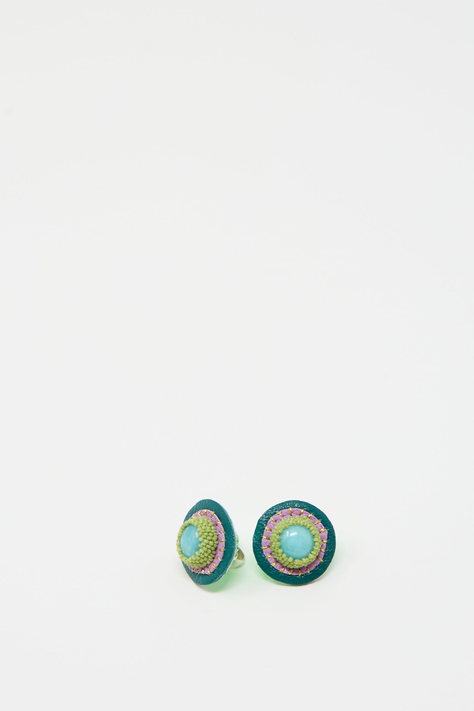 A pair of round, colorful Stud Earrings in Amazonite by Robin Mollicone, featuring a central amazonite stone and intricate beadwork detailing on a simple white background.