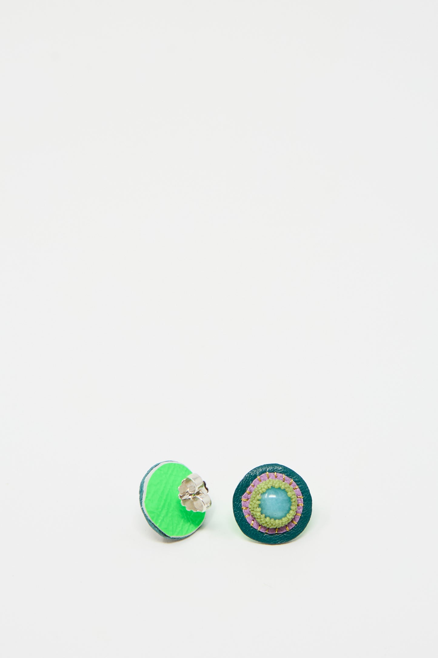 A pair of circular, handmade Robin Mollicone Stud Earrings in Amazonite displayed on a white background. One earring showcases a green outer ring and a blue inner ring with white and pink accents; the other highlights amazonite in the center, enhancing its similar design.