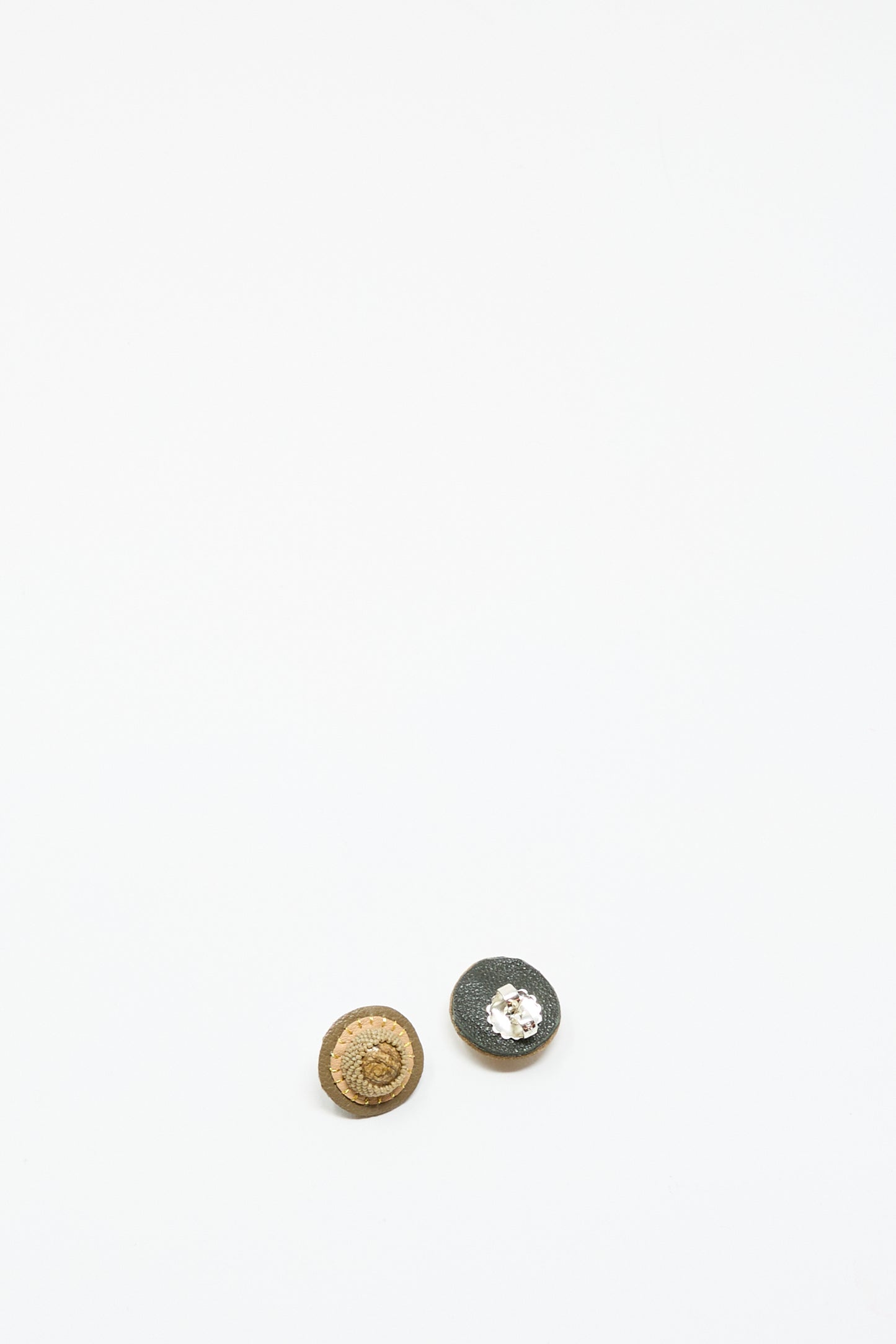 Two small, round Robin Mollicone Stud Earrings in Brown with Picture Jasper are displayed on a plain white surface near the bottom of the image.