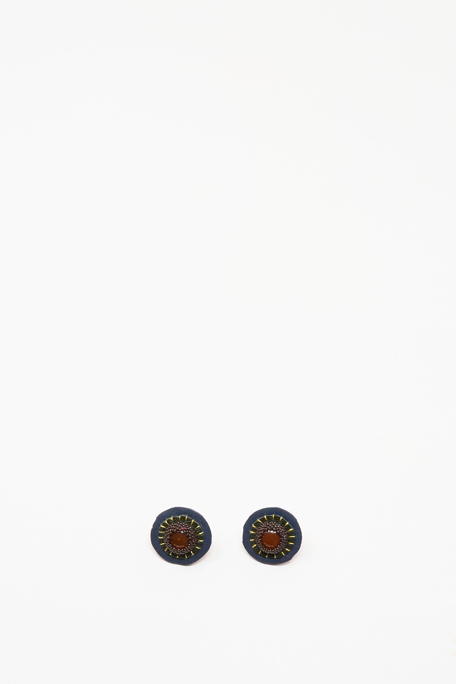 Robin Mollicone's Stud Earrings in Carnelian feature handmade round studs with a dark blue outer ring, brown leather center, and yellow stitched accents, shown on a white background.