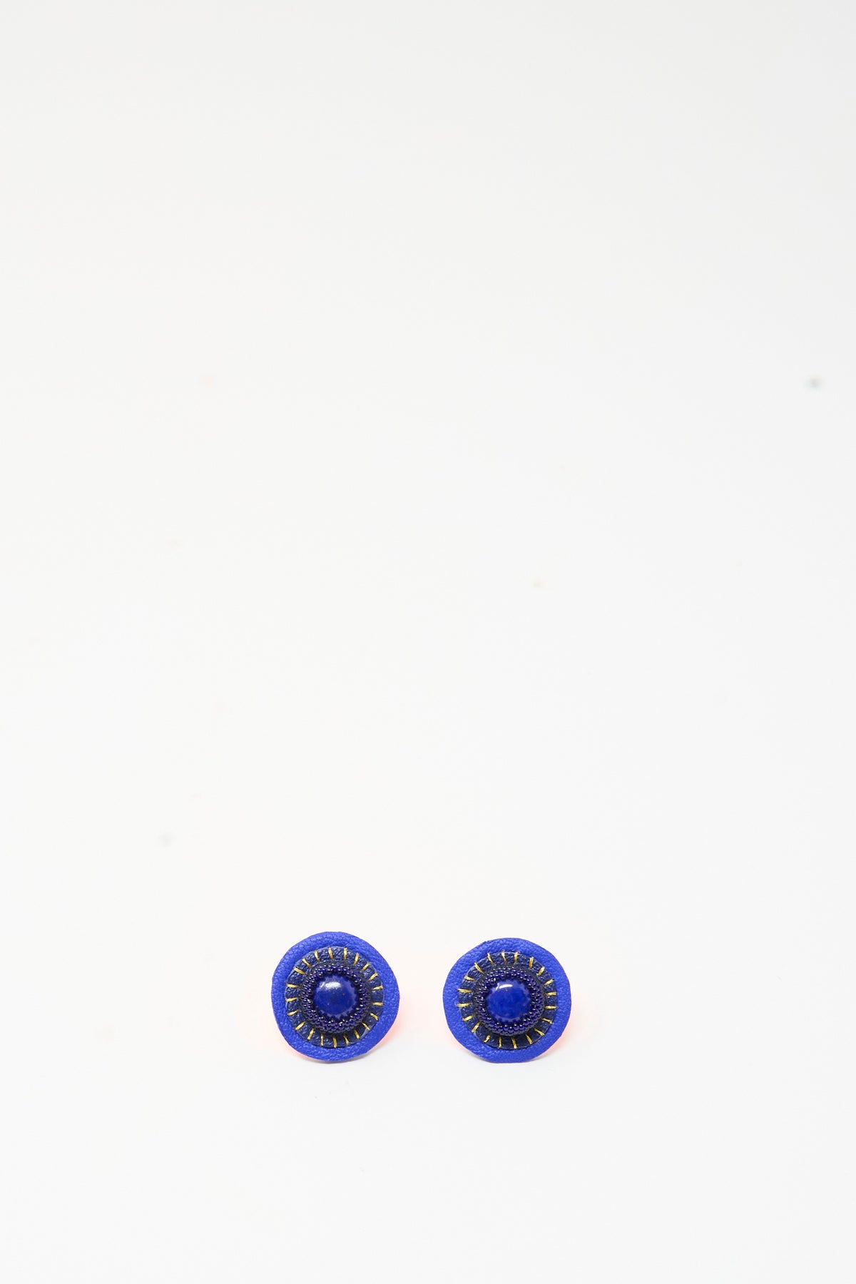 Robin Mollicone Stud Earrings in Lapis featuring a blue center stone surrounded by gold stitching and a navy blue border.