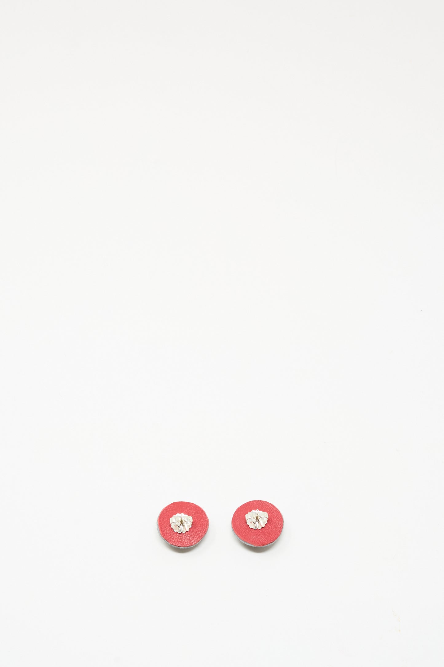 Two small round Stud Earrings in Onyx by Robin Mollicone, featuring a beige or light center, are placed side by side on a plain white background.