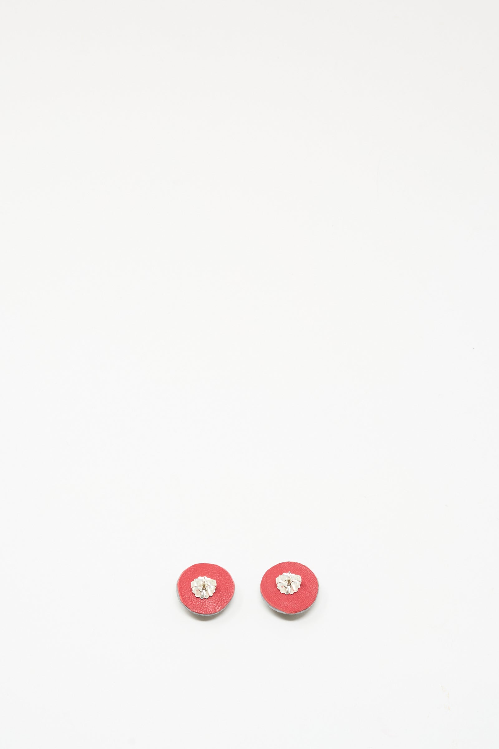 Two small round Stud Earrings in Onyx by Robin Mollicone, featuring a beige or light center, are placed side by side on a plain white background.