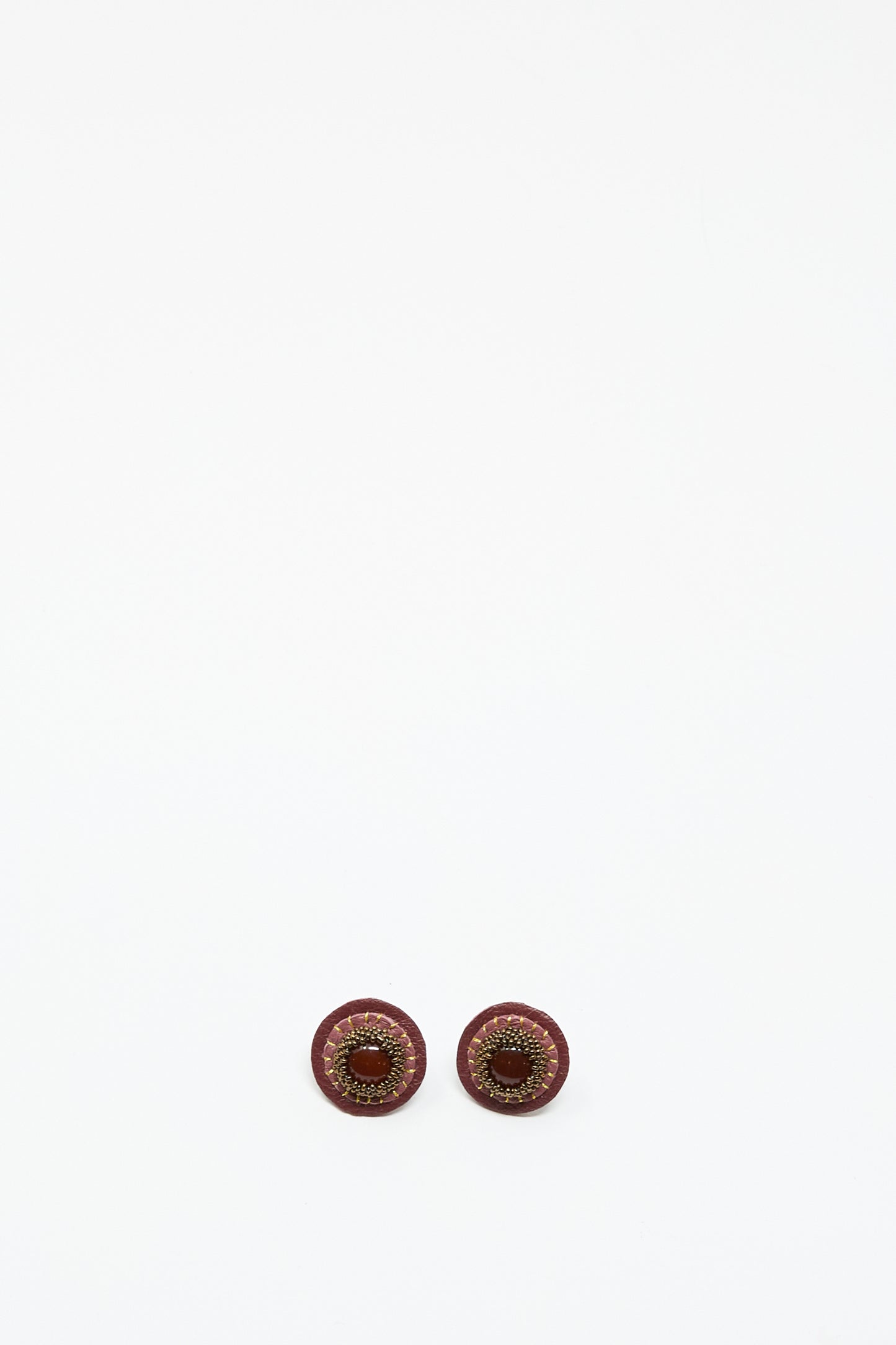 Two round, pink handmade stud earrings with carnelian by Robin Mollicone are placed side by side on a plain white background.