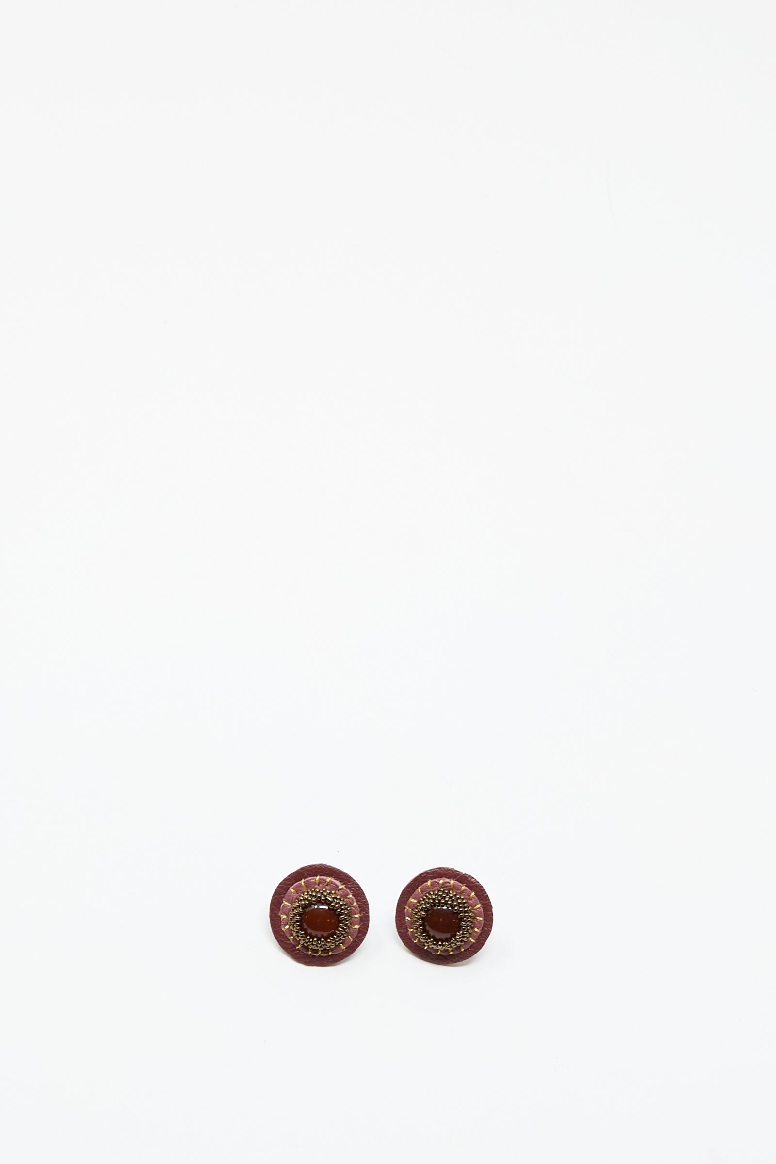 Two round, pink handmade stud earrings with carnelian by Robin Mollicone are placed side by side on a plain white background.