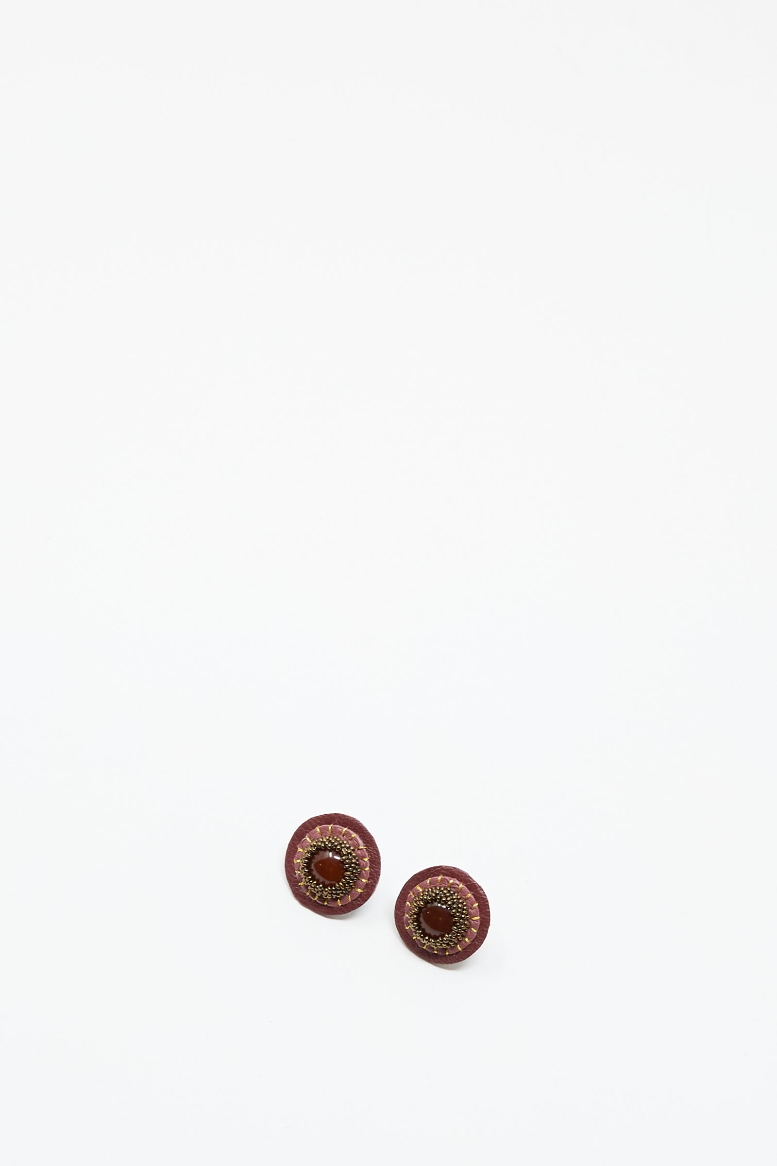 Two round, pink handmade stud earrings with carnelian by Robin Mollicone are displayed on a plain white background, resembling decorative buttons.