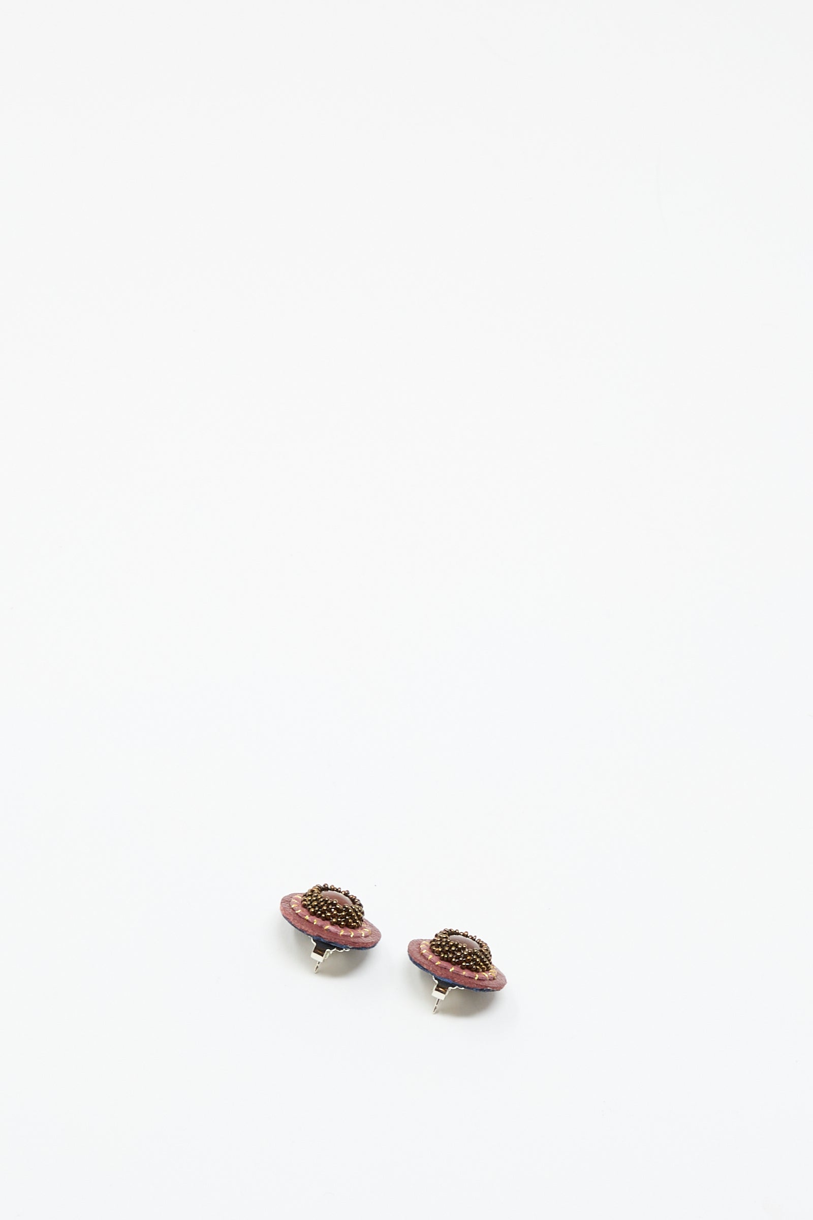 The Robin Mollicone Stud Earrings in Pink with Carnelian feature small, planet-inspired designs with pink rings and dark carnelian centers, shown against a plain white background.