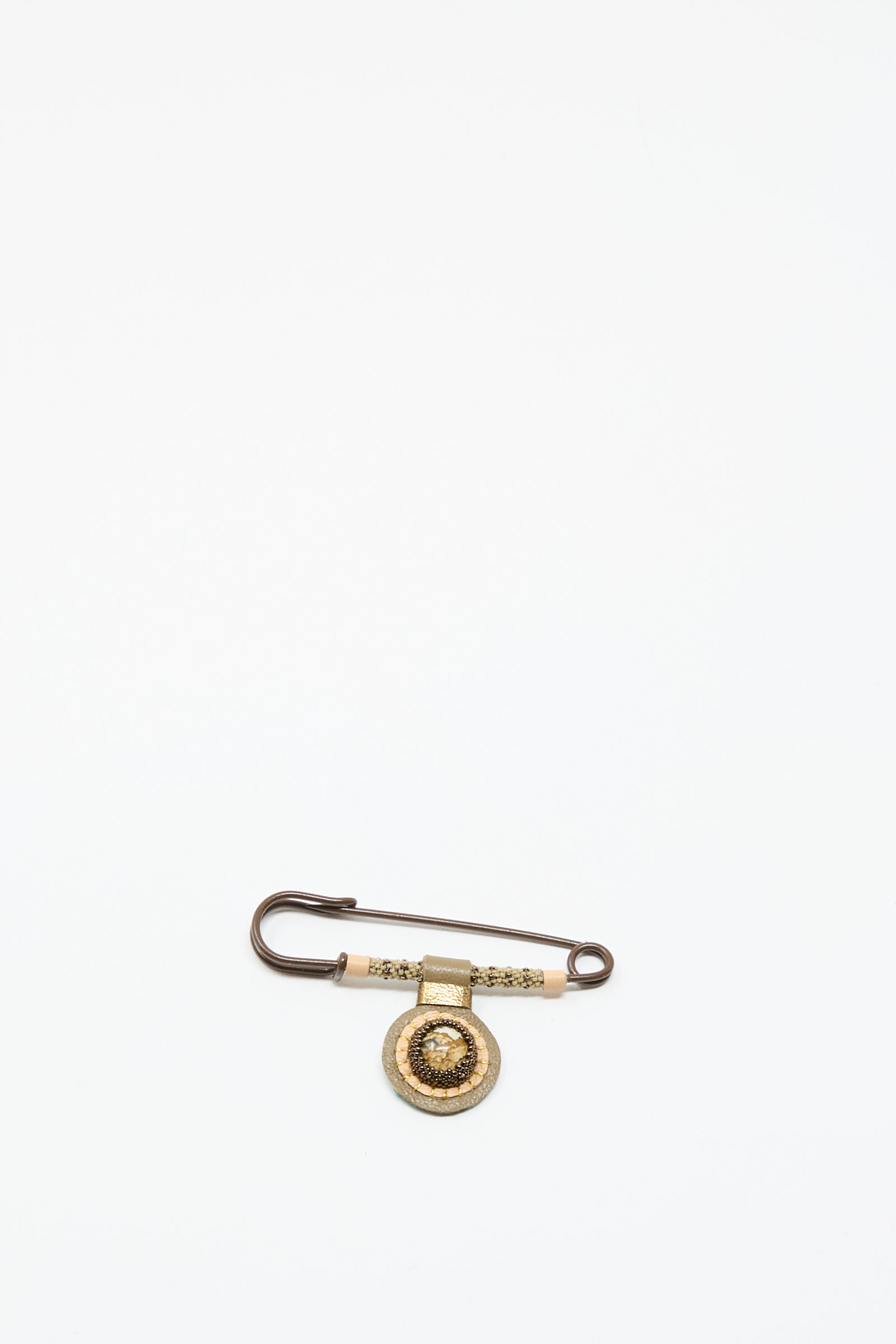 The Gem Drop Safety Pin in Brown with Picture Jasper by Robin Mollicone, a handmade beaded pin featuring a decorative gold circular pendant, is displayed against a plain white background.