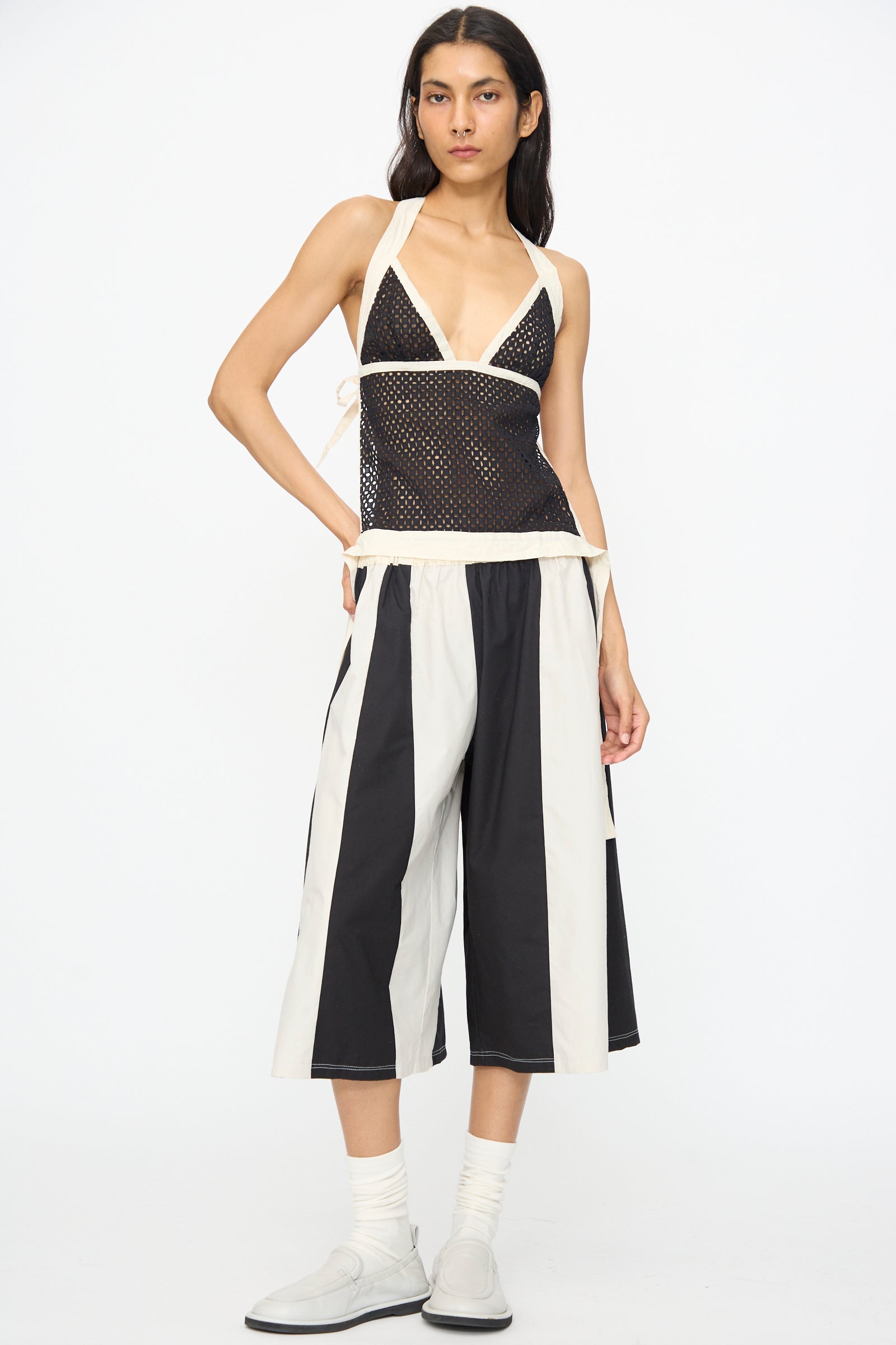 Model wears the SC103 Cotton Eyelet Gaze Tank in Eclipse, paired with wide-leg black and white striped culotte pants, white socks, and light gray shoes, standing against a plain white background.