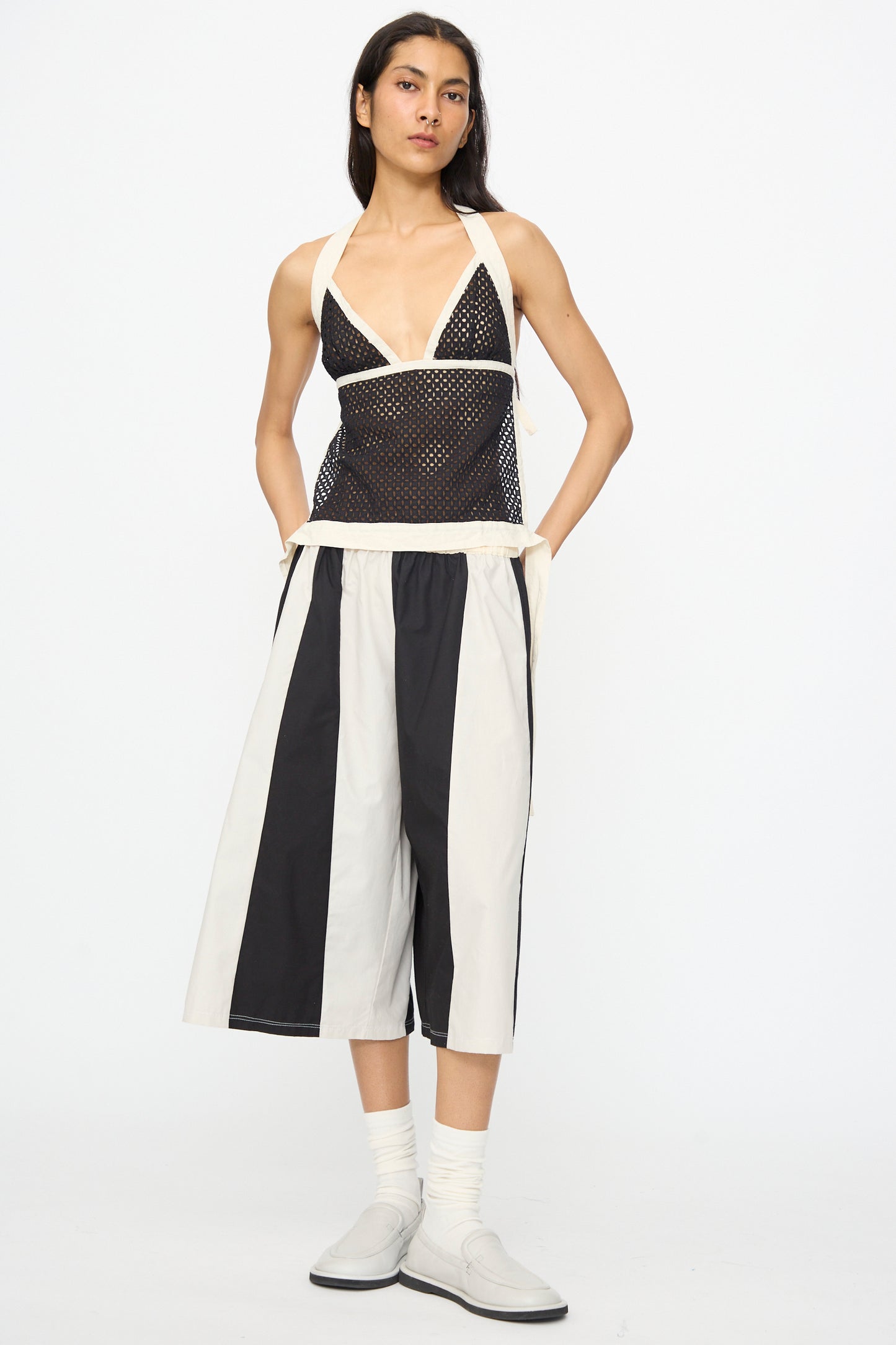 A person wears the SC103 Cotton Eyelet Gaze Tank in Eclipse, paired with wide black and white striped shorts, white socks, and slip-on shoes against a plain background—an ensemble that channels New York City style.