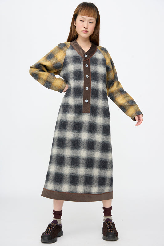A Cotton Flannel Frame Dress in Scholar, a long-sleeved midi dress in plaid with a V-neck, buttoned placket, and dark trim, worn with sneakers and two-toned socks.
