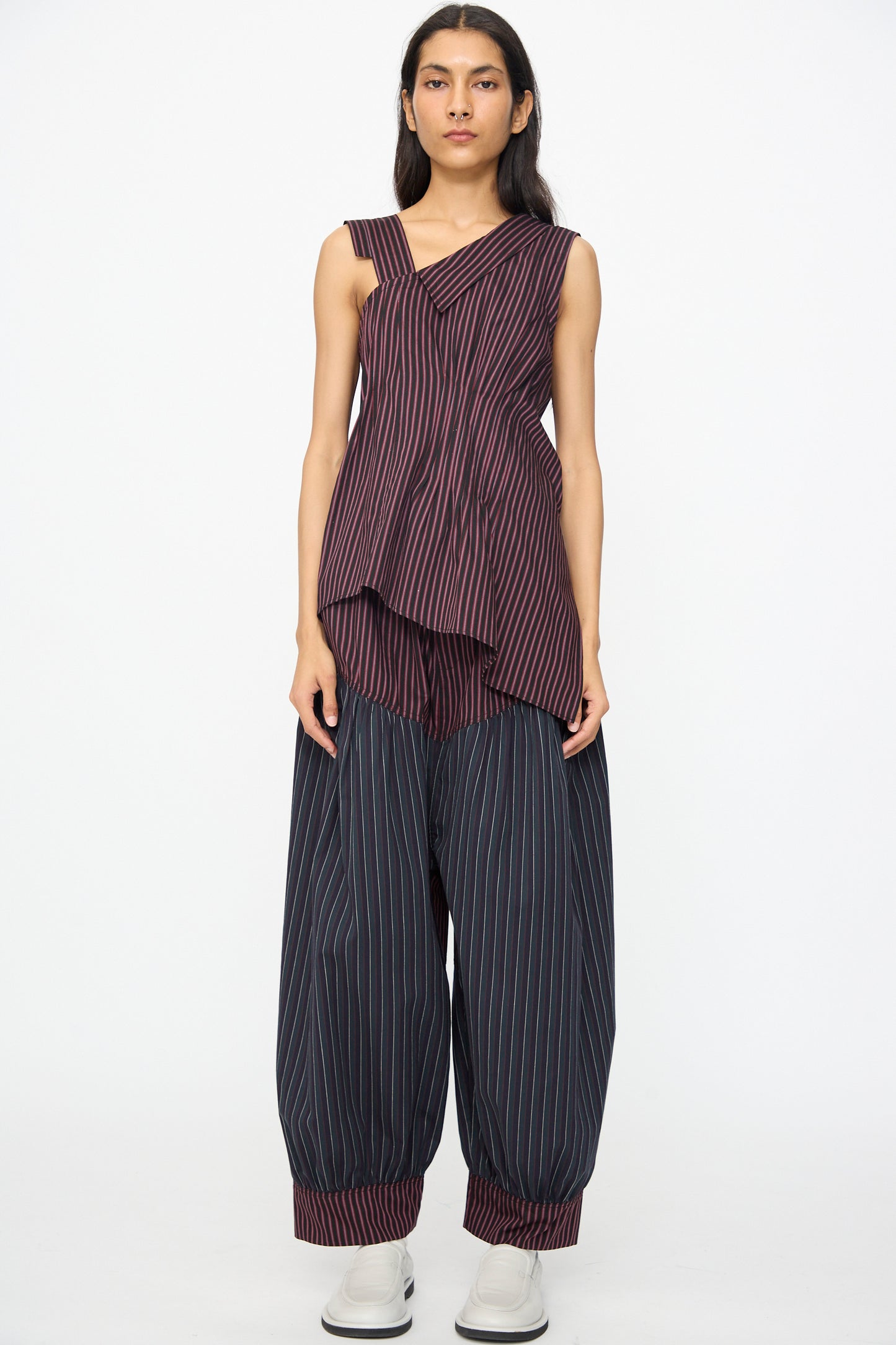 A person models the SC103 Cotton Suiting Crescent Pants in Celestine Stripe, featuring a wide-leg, pinstriped, slouchy fit with cuffs, paired with a sleeveless asymmetrical striped cotton top against a plain white background.