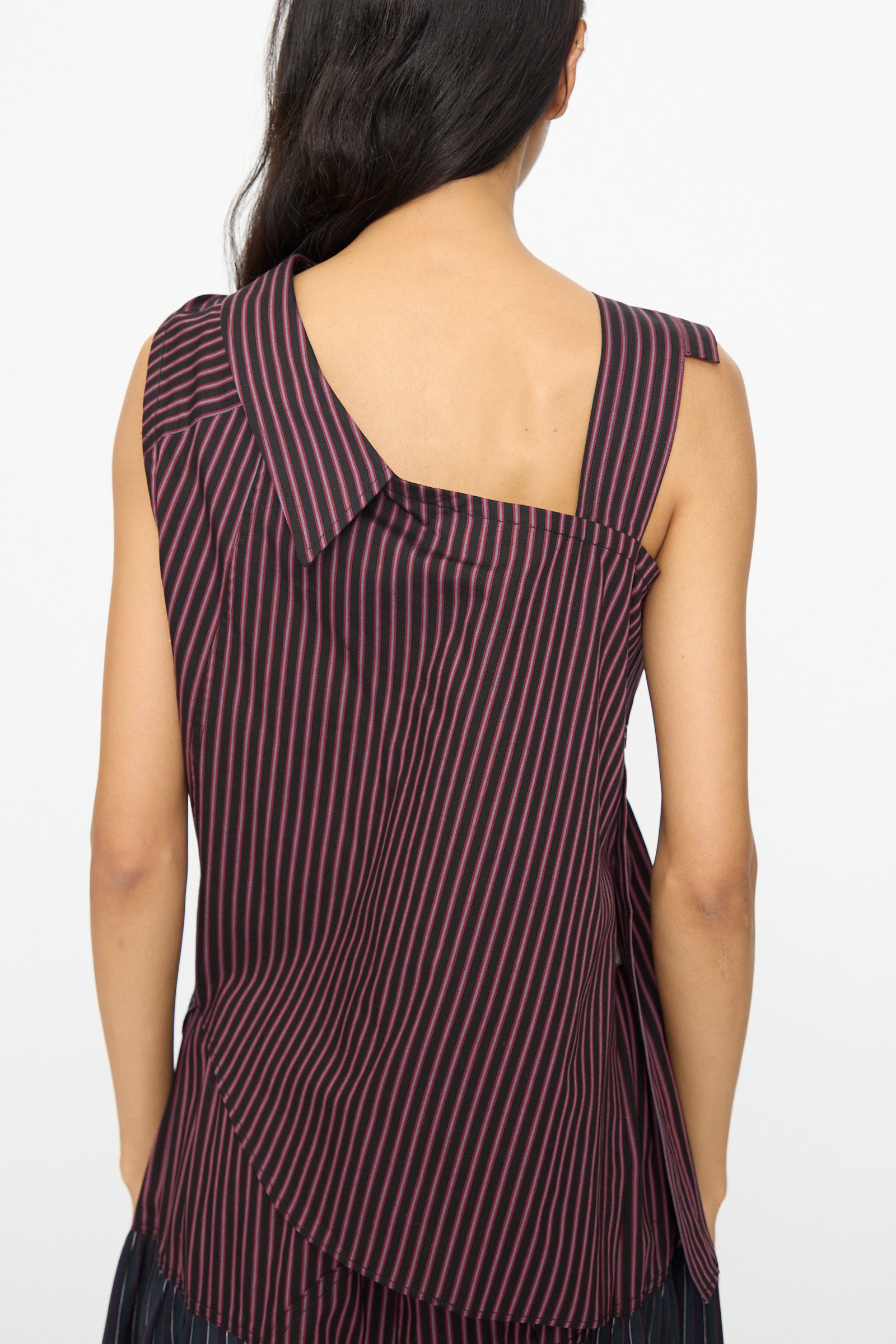 Seen from behind, a person wears the SC103 Cotton Suiting Solstice Top in Celestine Stripe—an asymmetrical sleeveless striped cotton top made in NYC.