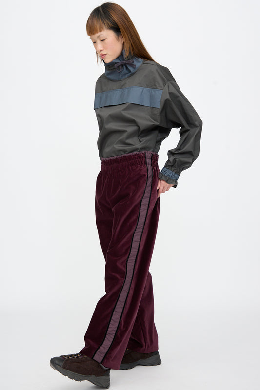 A person wearing a dark grey windbreaker and SC103 Cotton Velvet Chord Pants in Noble, featuring straight-leg and stripe down the leg.
