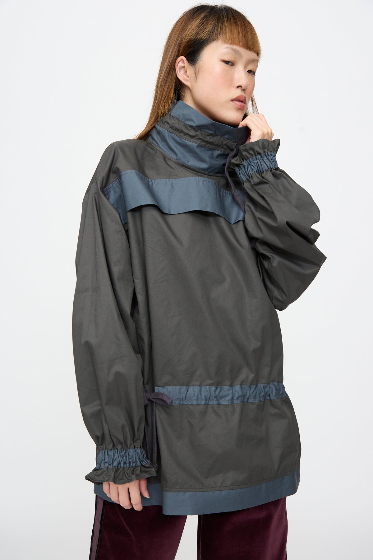 A person wearing a relaxed-fit, dark grey Crisp Cotton Incline Tunic in Twilight with blue trim and gathered cuffs.