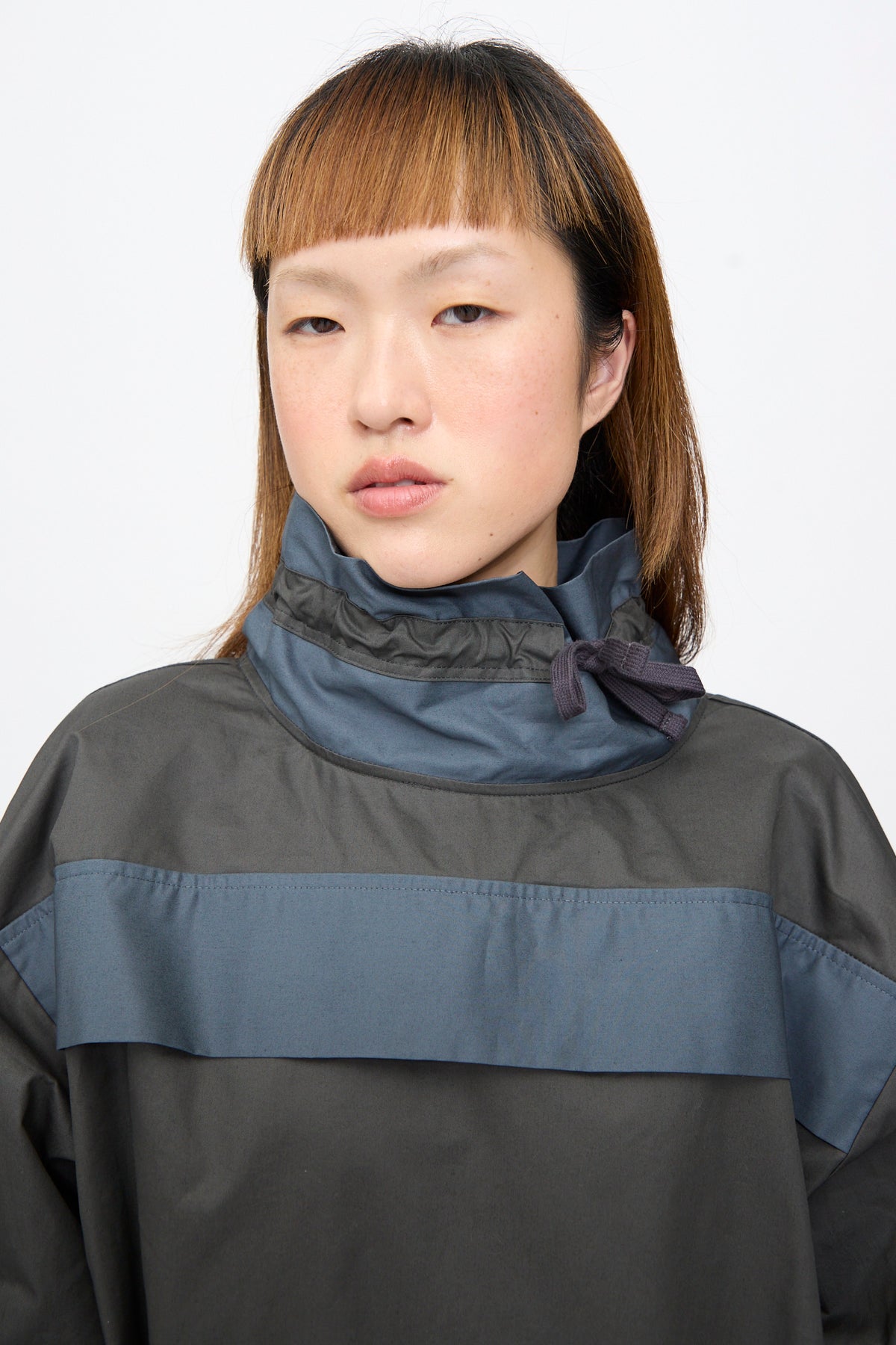 A person wears the SC103 Crisp Cotton Incline Tunic in Twilight, a dark gray, two-tone cotton tunic with standing drawstring collar.