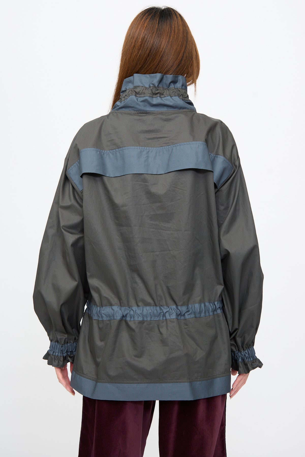 Rear view of a person wearing a dark grey, relaxed fit Crisp Cotton Incline Tunic in Twilight with blue trim on the collar, back yoke, waist, and cuffs.
