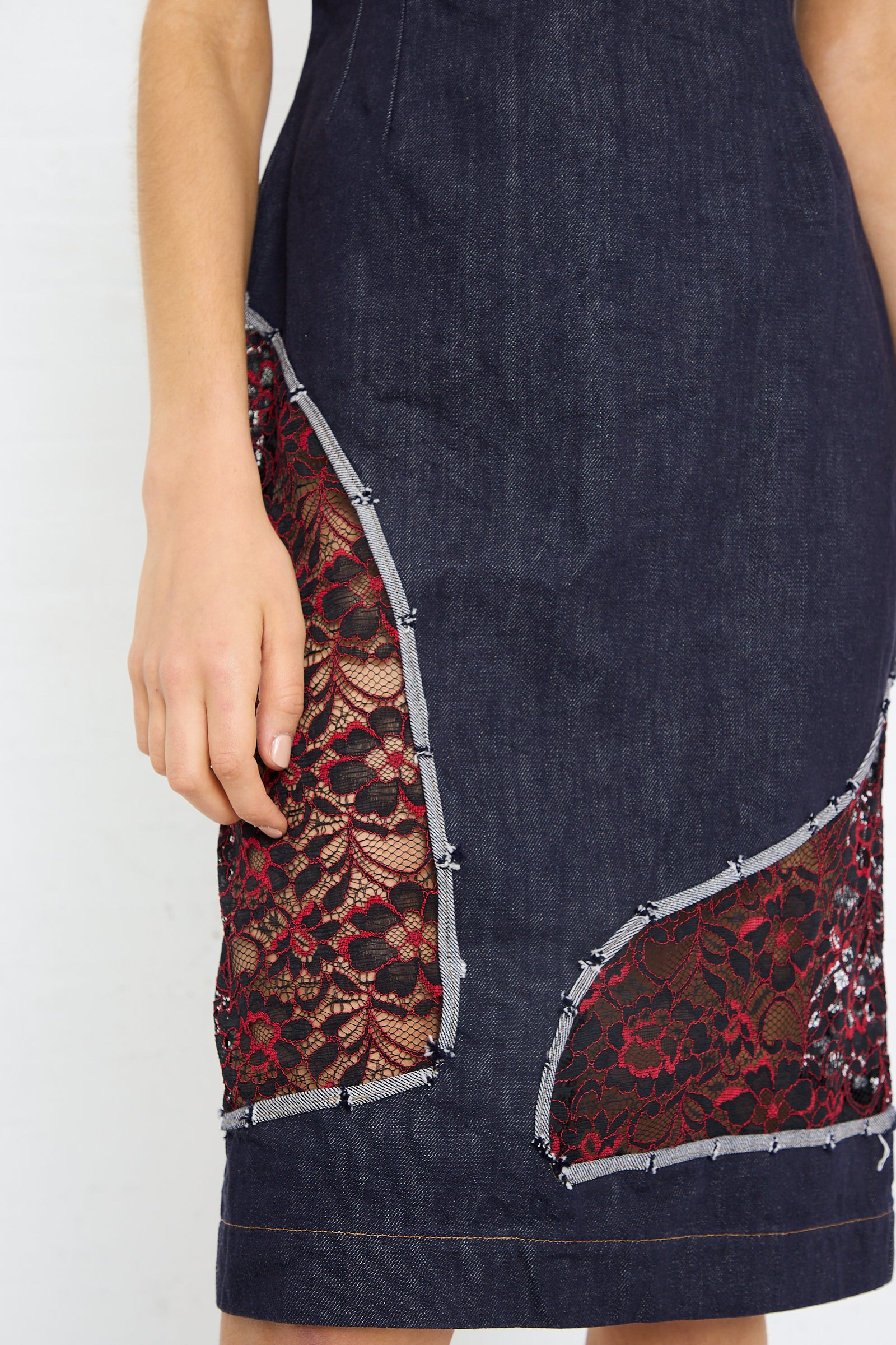Close-up of a sleeveless SC103 denim motto dress in weft with cutout lace detailing on the sides.