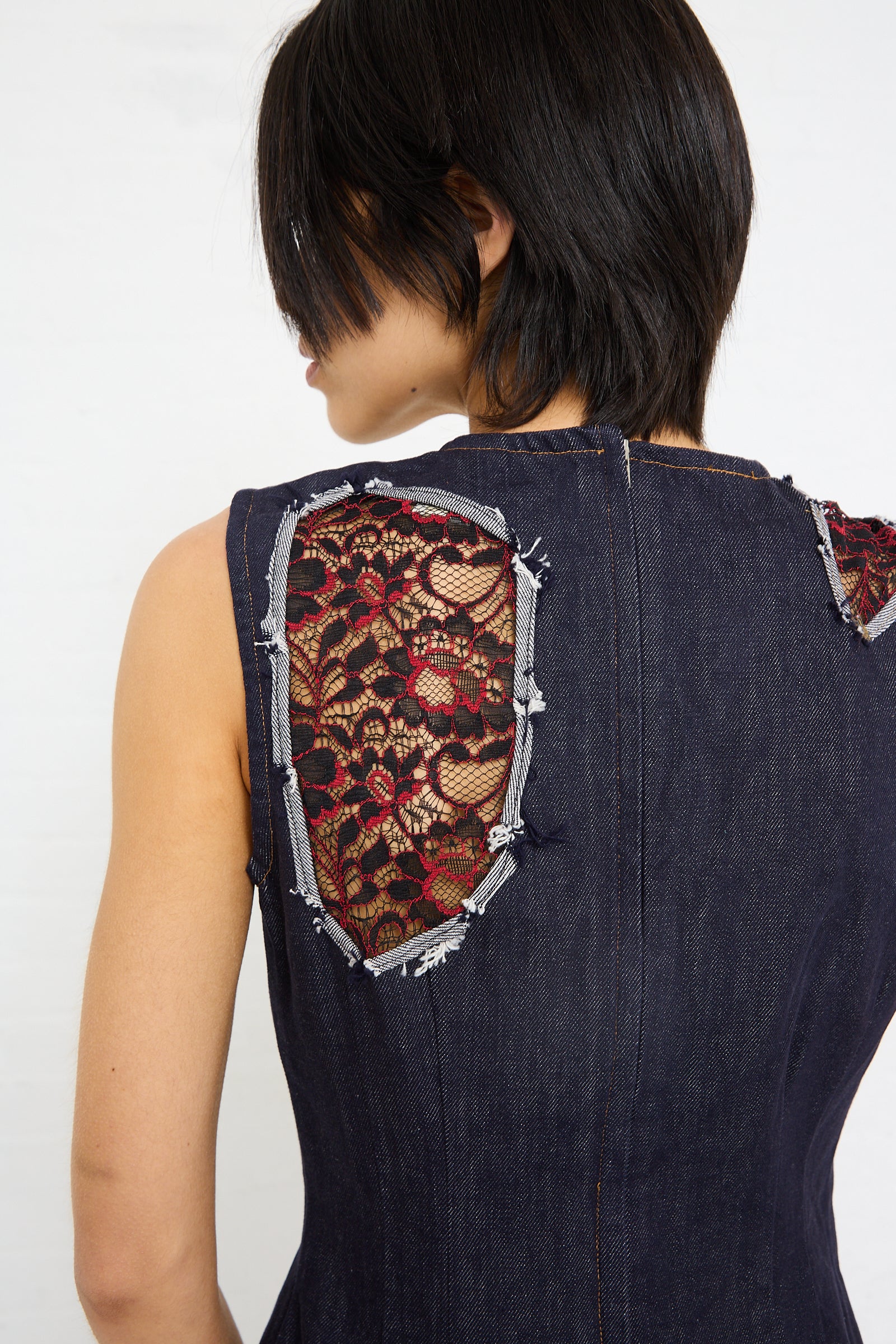 Woman wearing a sleeveless SC103 Denim Motto Dress in Weft with cutout lace detailing on the back.