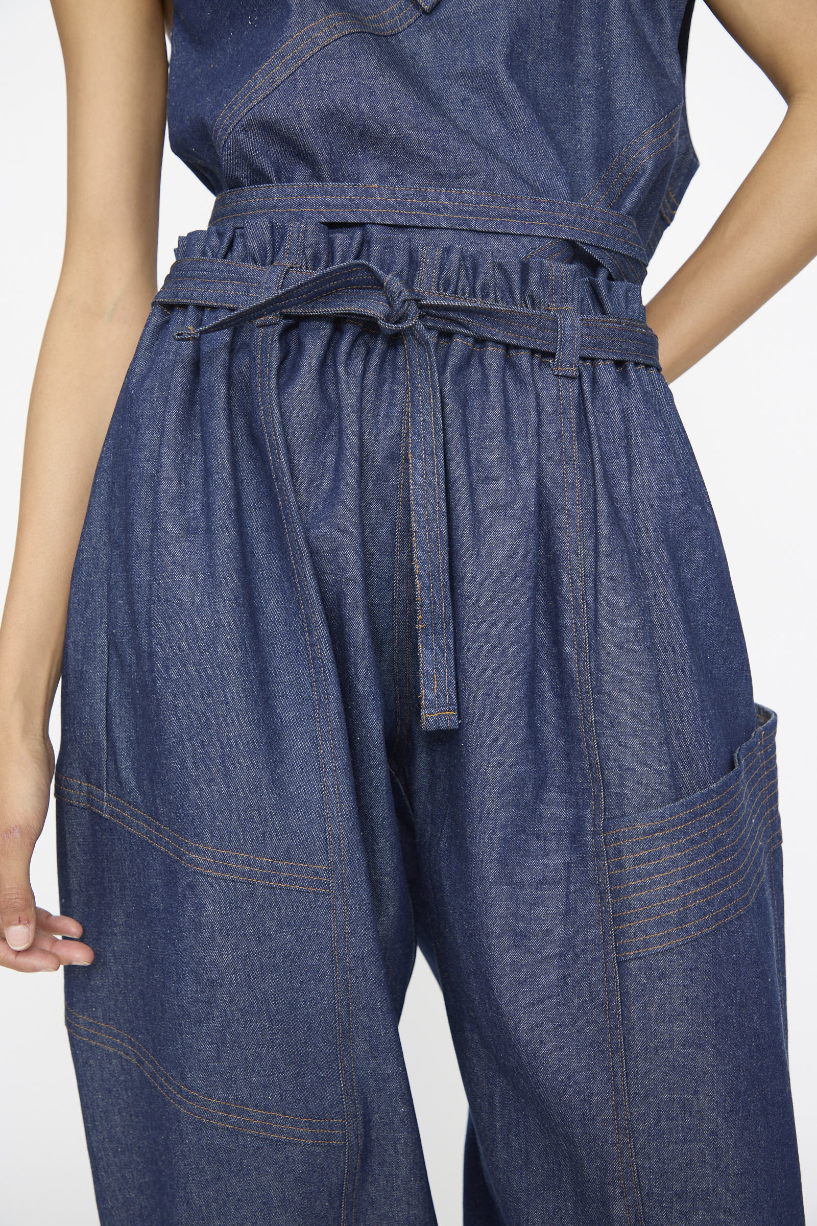 Wearing SC103's Denim Vault Pants in Soft Indigo—high-waisted, wide-leg with a paperbag drawstring waist, belted tie, large patch pockets, and visible stitching for a relaxed fit.