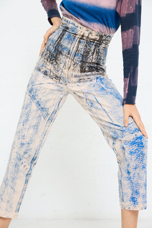 Woman in SC103 blue and beige graphic Lace Print Cotton Legend Trouser in Ink cropped trousers and a blue top posing with one hand on her hip.