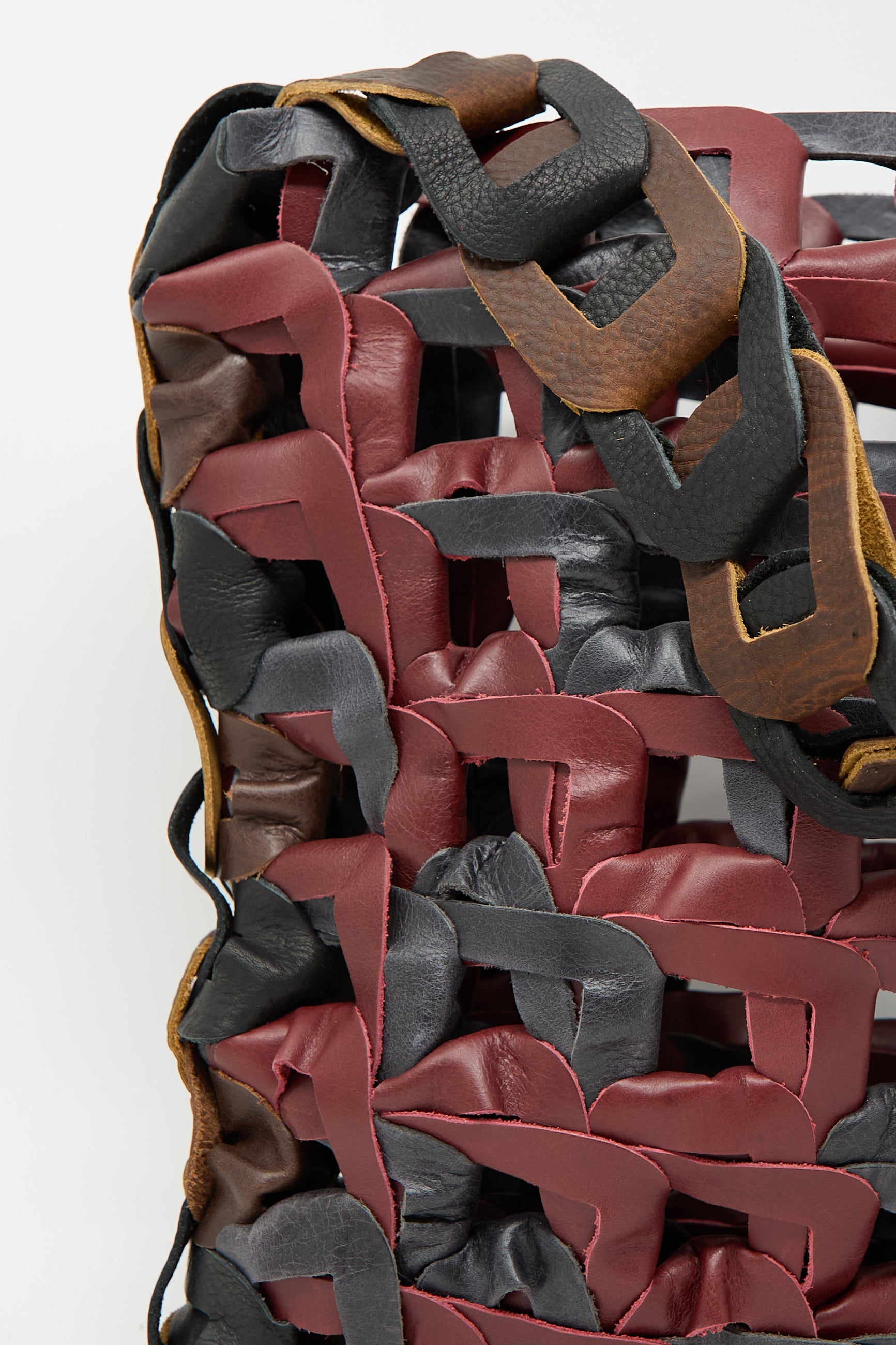 Close-up of the intricately woven Leather Medium Links Tote in Cinema by SC103, showcasing red, brown, and black strips creating a textured pattern.