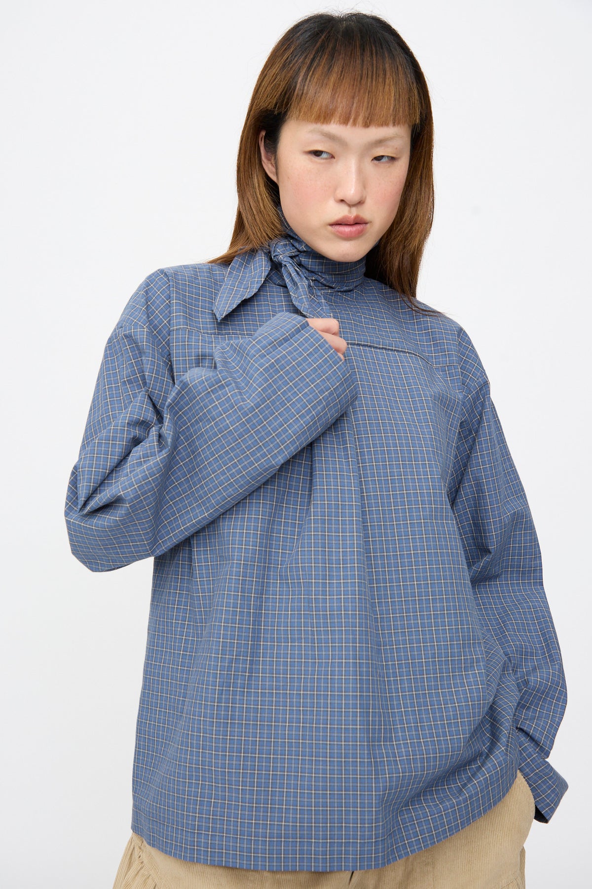 SC103 Plaid Poplin Compass Blouse in Aerial, a blue plaid long-sleeve cotton blouse featuring a high neck and tie detail.