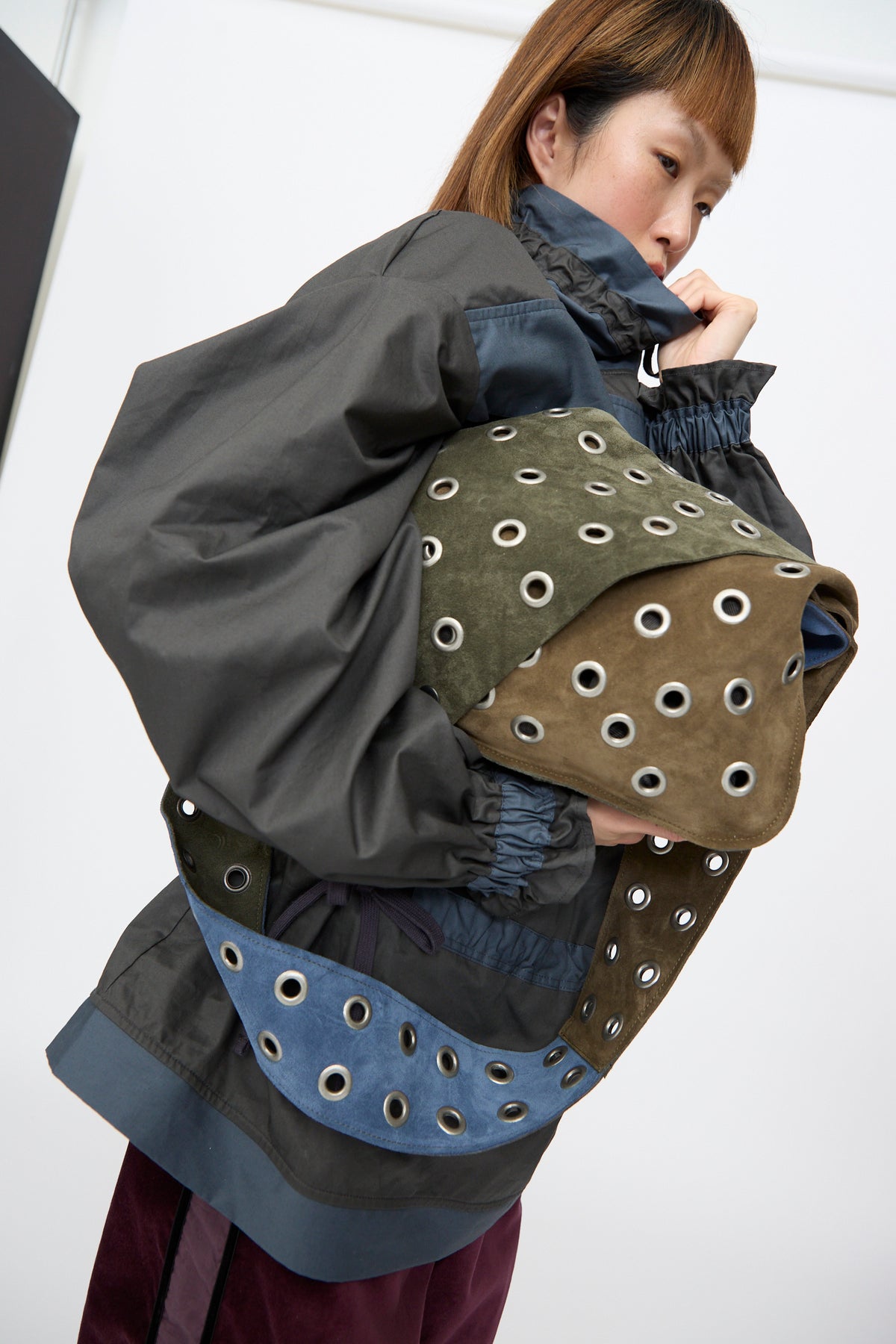 Person carrying a multi-colored SC103 Suede Leather Record Messenger in Abyss featuring silver metal grommets across the body and strap.