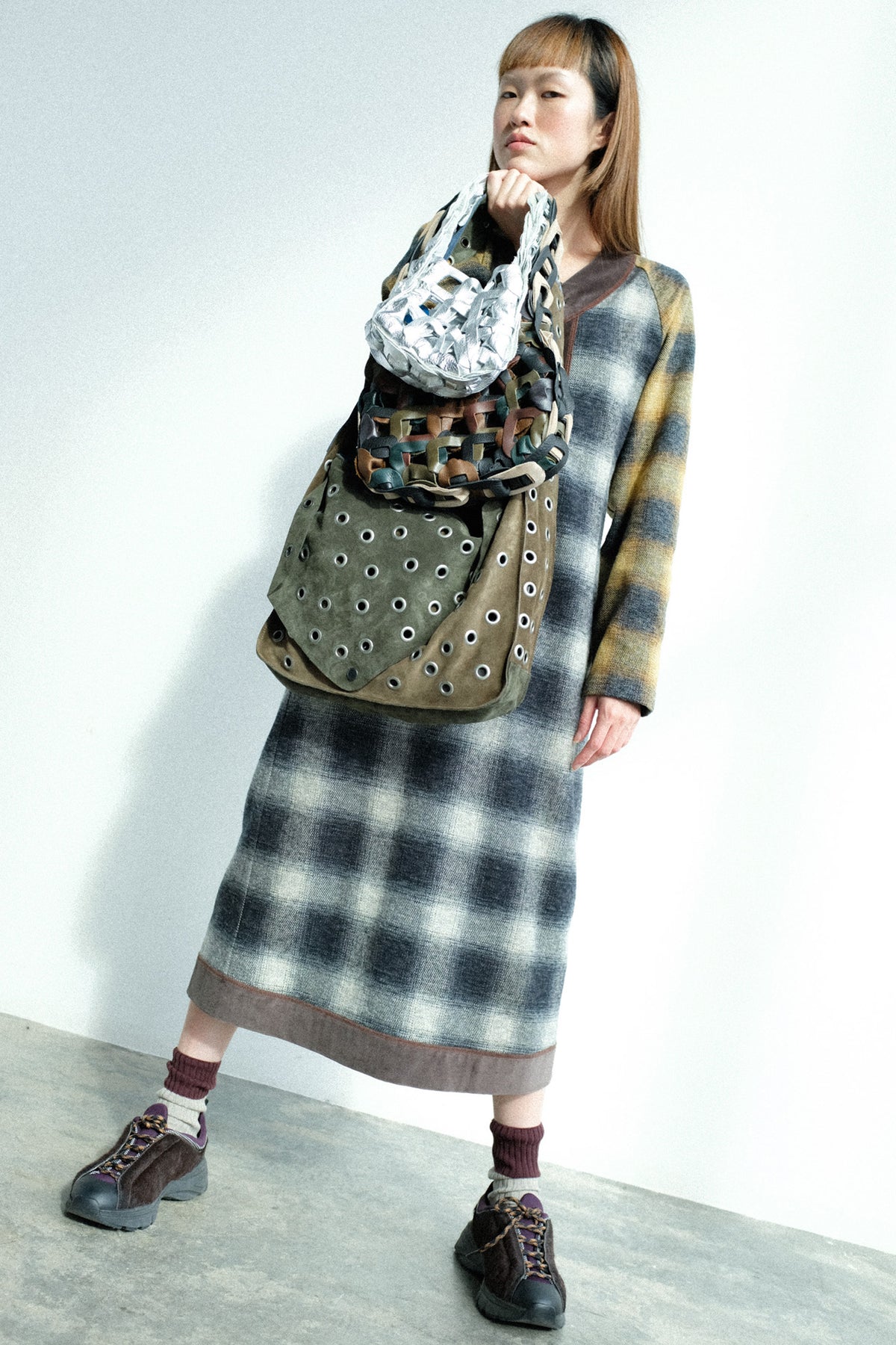 A woman holding SC103 bags against a white wall and concrete floor.