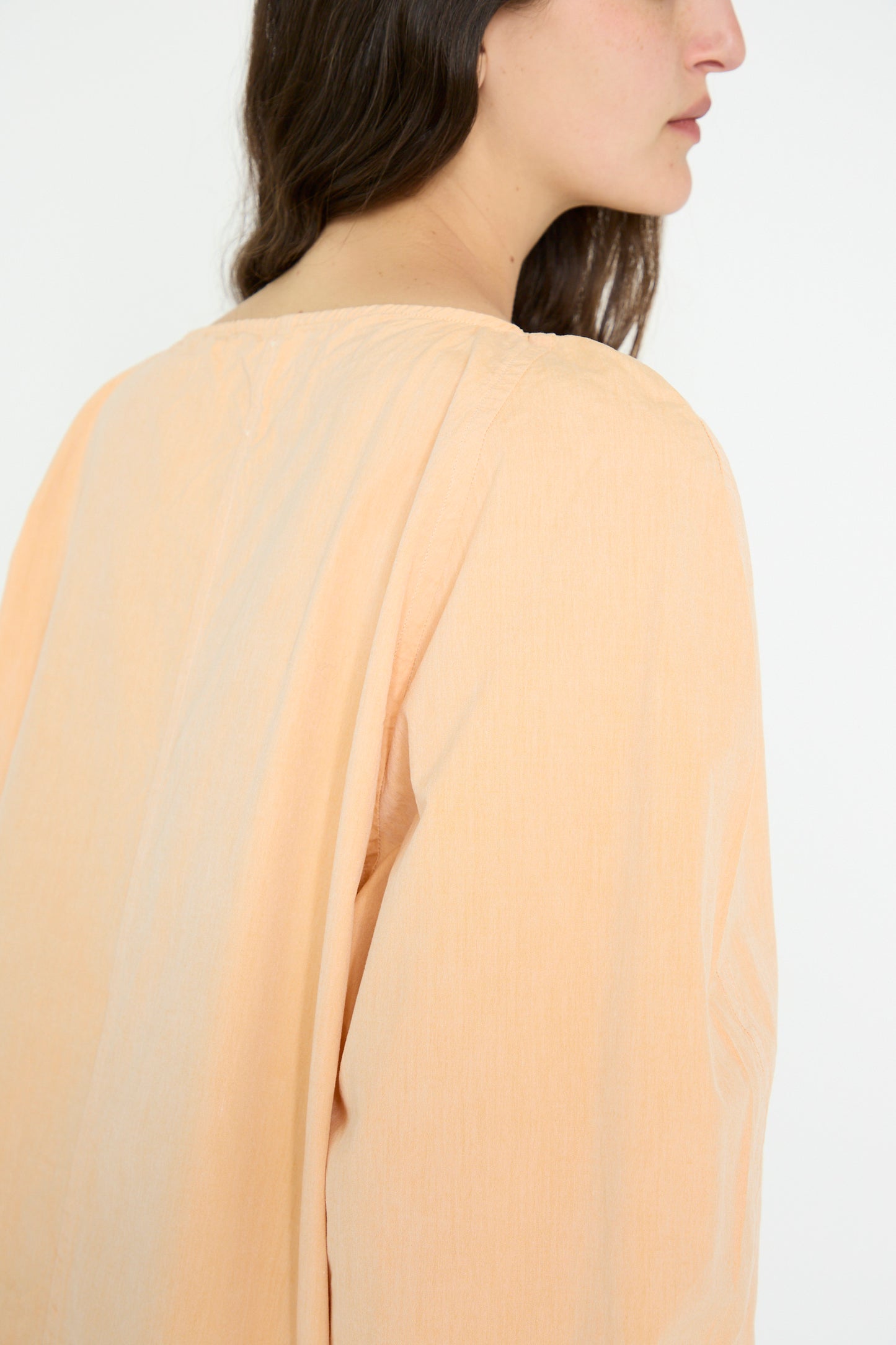 A side profile captures a person wearing the oversized Cotton Tiga Top in dusty peach by SONO, made from organic cotton, seen from shoulder to mid-back against a neutral backdrop.