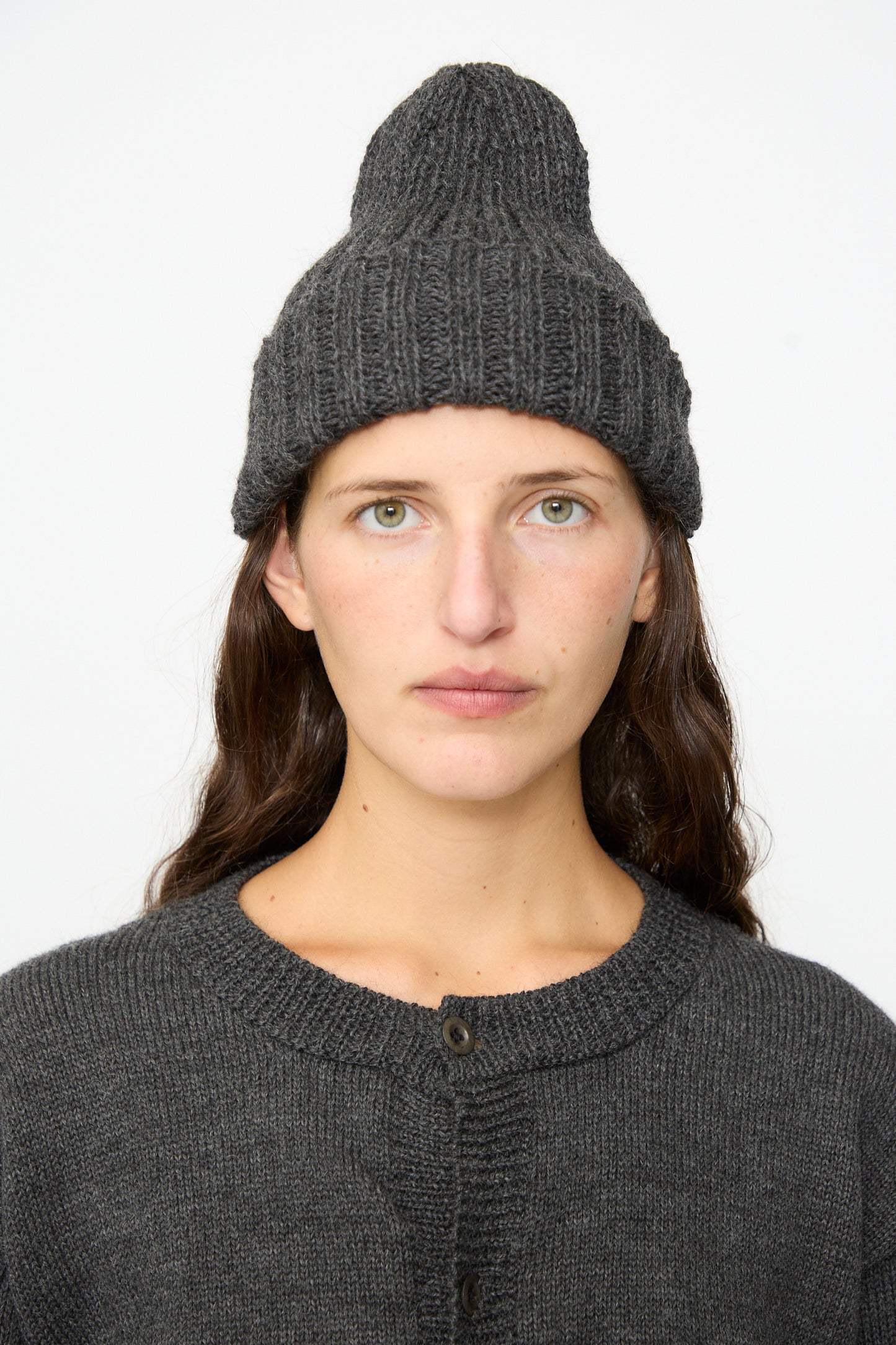 A person wearing the SONO Gyu Beanie in Charcoal and a matching sweater looks straight at the camera against a plain light background.