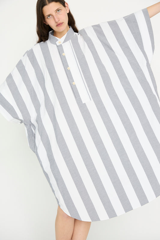 A person wearing the Octo Overshirt in Stripe by SONO, made from organic cotton with white and gray vertical stripes, is standing against a plain background.