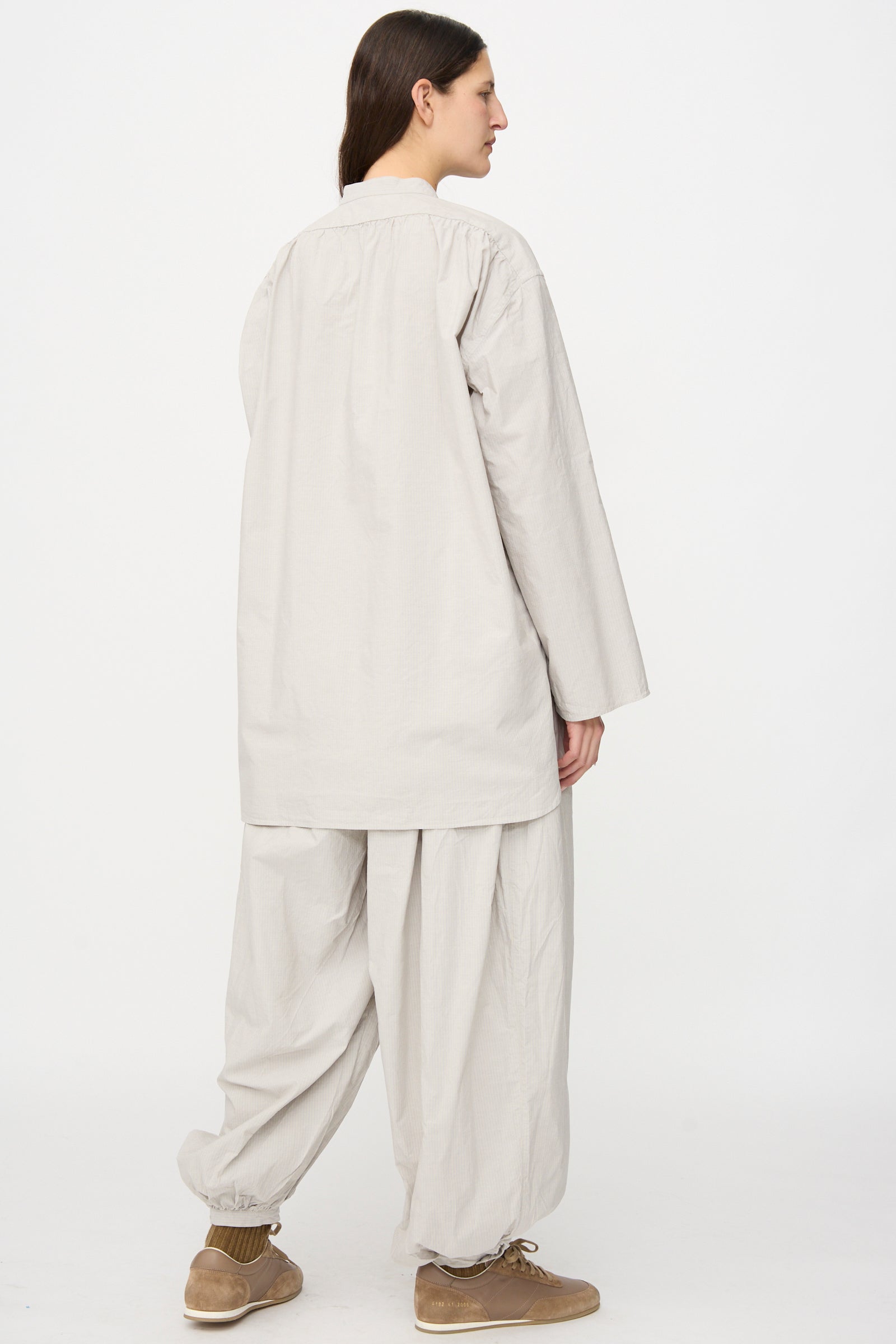 A person faces away, wearing the SONO Shaman Shirt in Dusty Fine Stripe with matching wide pants and brown shoes, standing against a plain white background.