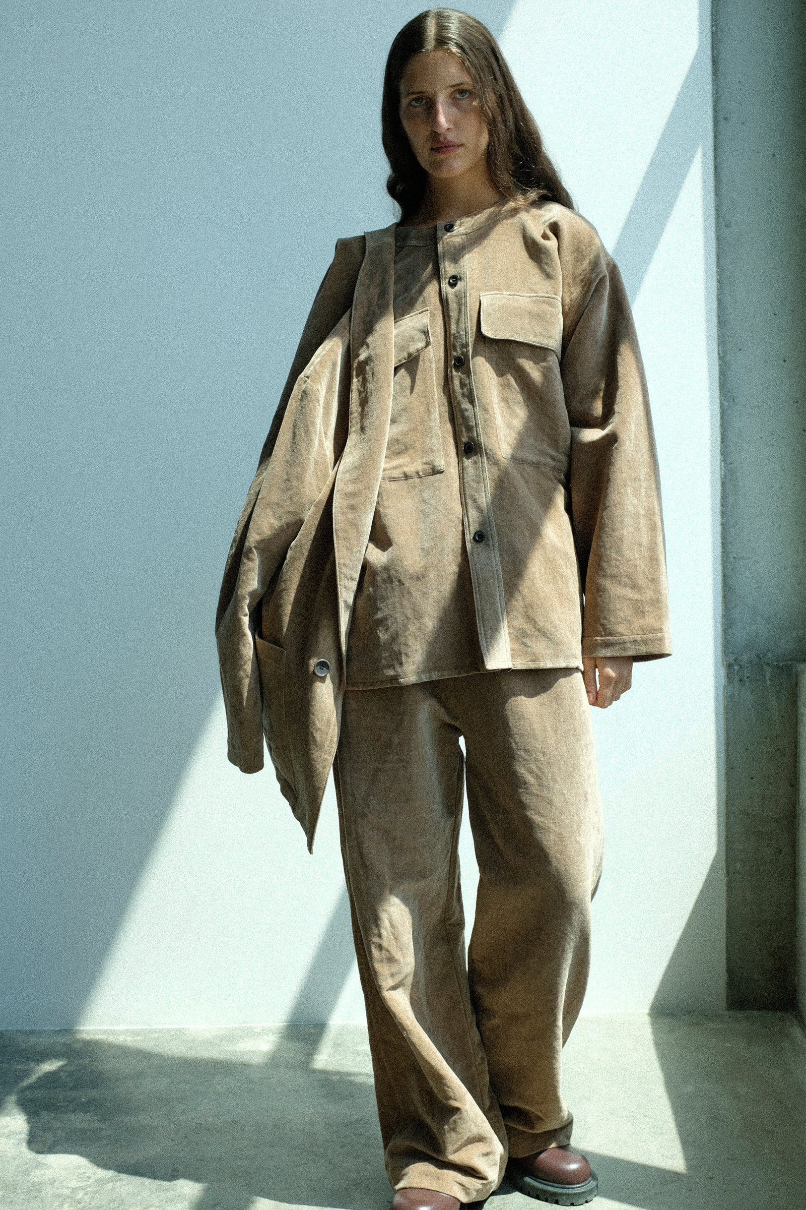 Person wearing a beige outfit standing against a light background