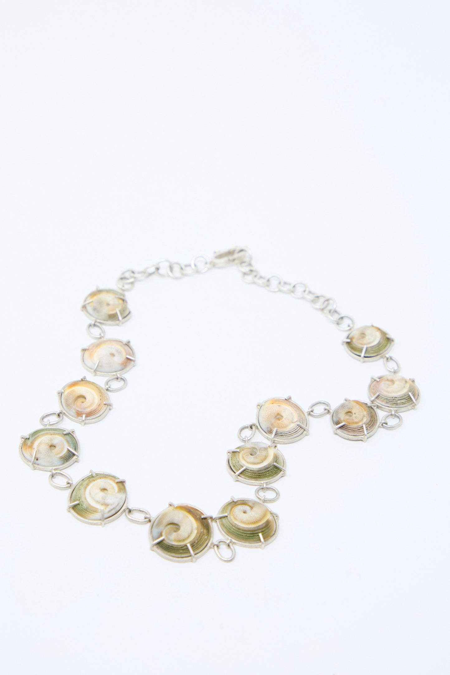 The Sterling Silver Necklace in Shell by La Mar: A handmade necklace made from sterling silver, and spiral shells arranged in a symmetrical design.