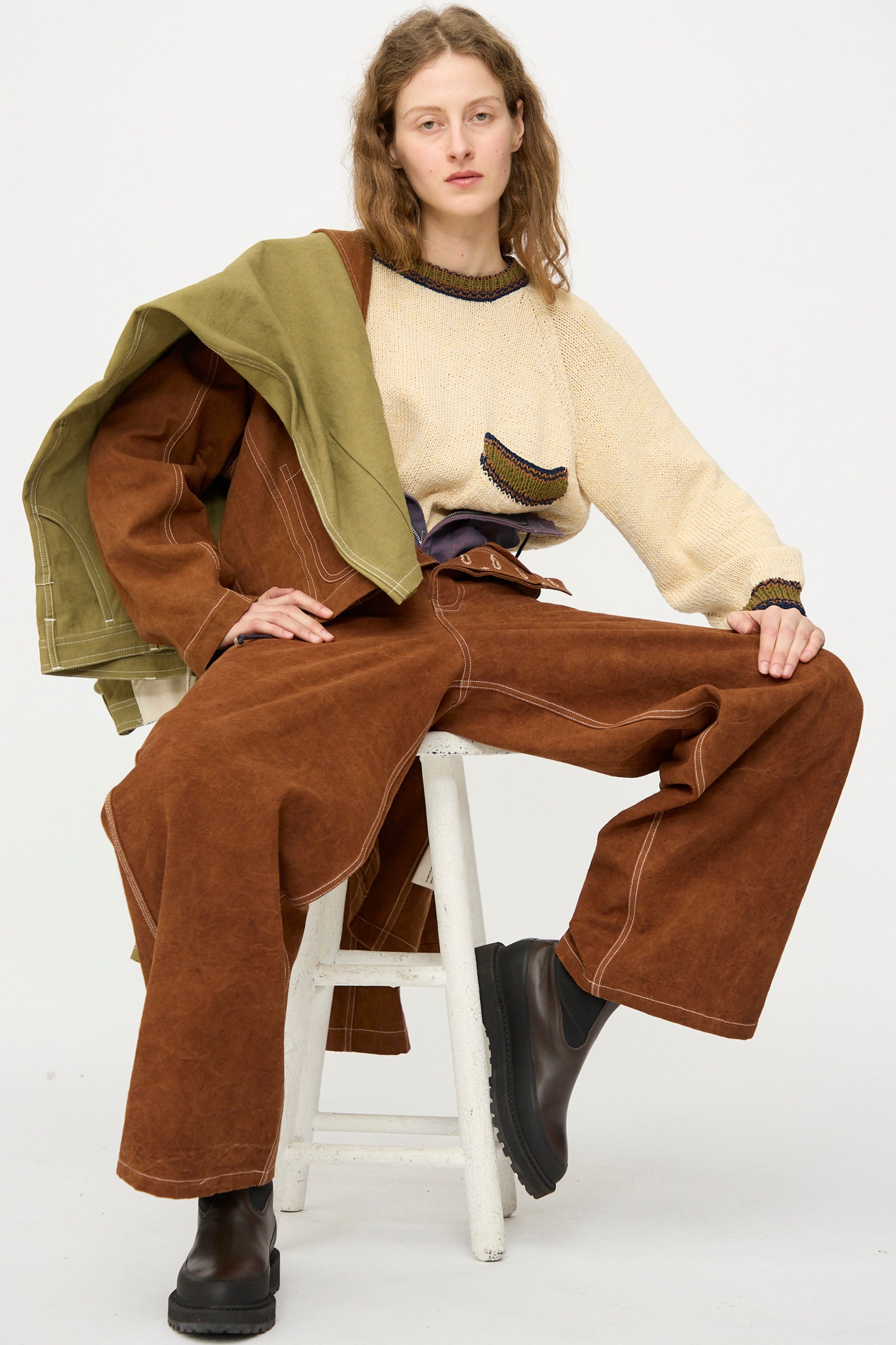 Person wearing pieces from Story mfg. PS26 collectioin sitting on a white stool.