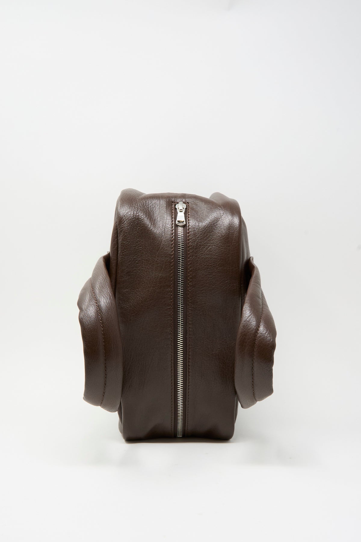Side view of a dark brown Leather The Bowling Bag featuring a prominent vertical zipper.