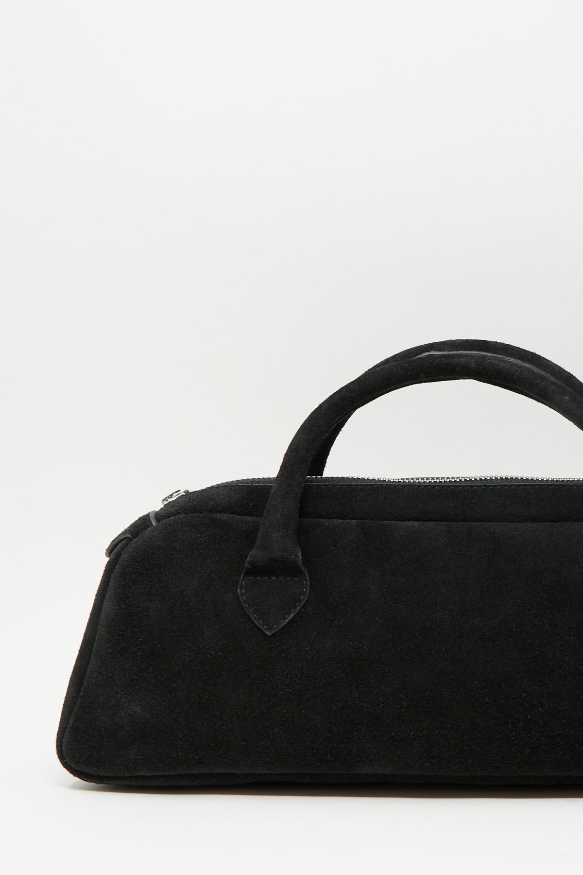Sabina Suede The Bottle Bag in black, a small suede handbag with a top handle and a zippered closure.