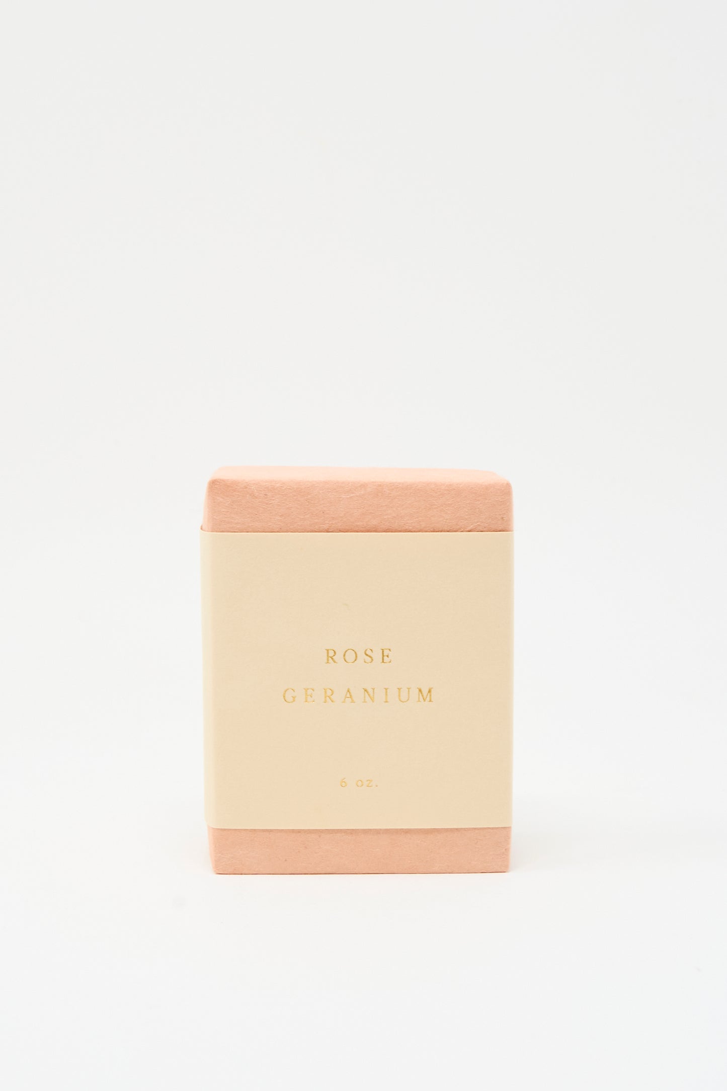 A rectangular SAIPUA Olive Oil Bar Soap in Rose Geranium, wrapped in pink with a cream label reading "Rose Geranium 6 oz.," stands against a white background, showcasing its floral essential oil blend and handcrafted quality.