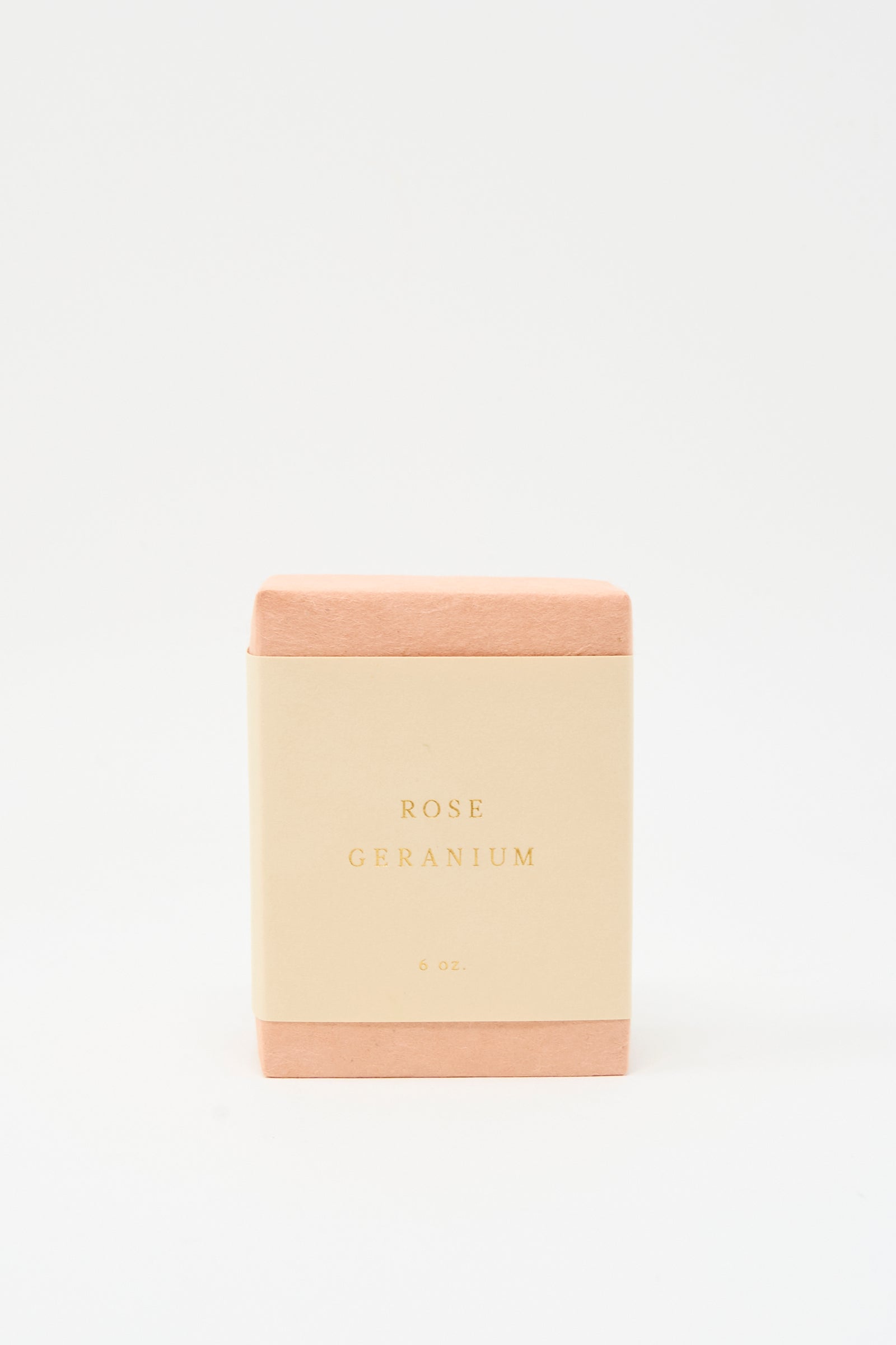 A rectangular SAIPUA Olive Oil Bar Soap in Rose Geranium, wrapped in pink with a cream label reading "Rose Geranium 6 oz.," stands against a white background, showcasing its floral essential oil blend and handcrafted quality.