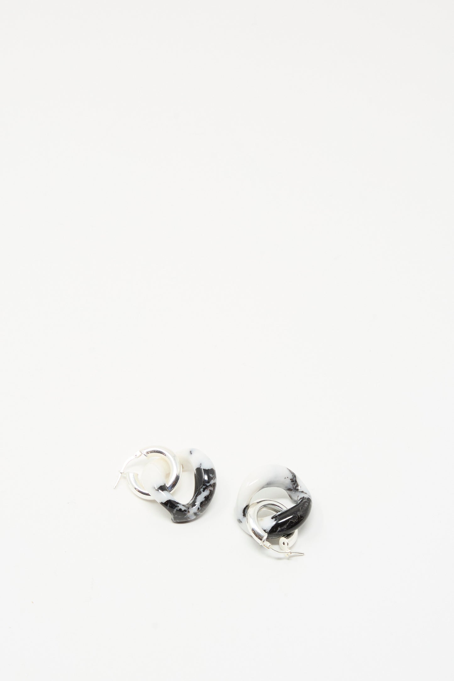 The Santangelo Bad Orb Earrings in Zebra Jasper are small, twisted sterling silver hoops featuring a bold black and white marbled pattern, shown against a plain white background.