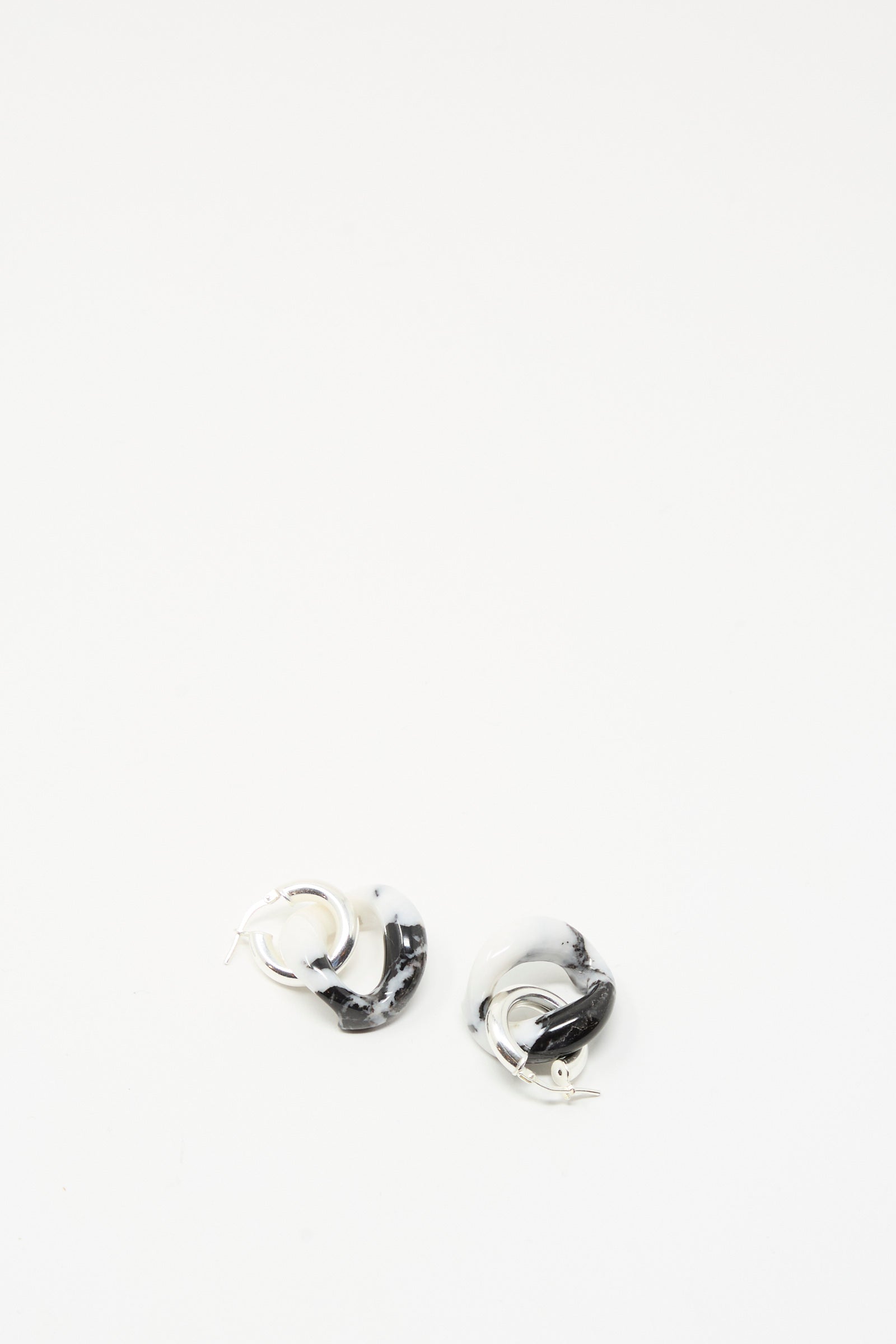 The Santangelo Bad Orb Earrings in Zebra Jasper are small, twisted sterling silver hoops featuring a bold black and white marbled pattern, shown against a plain white background.