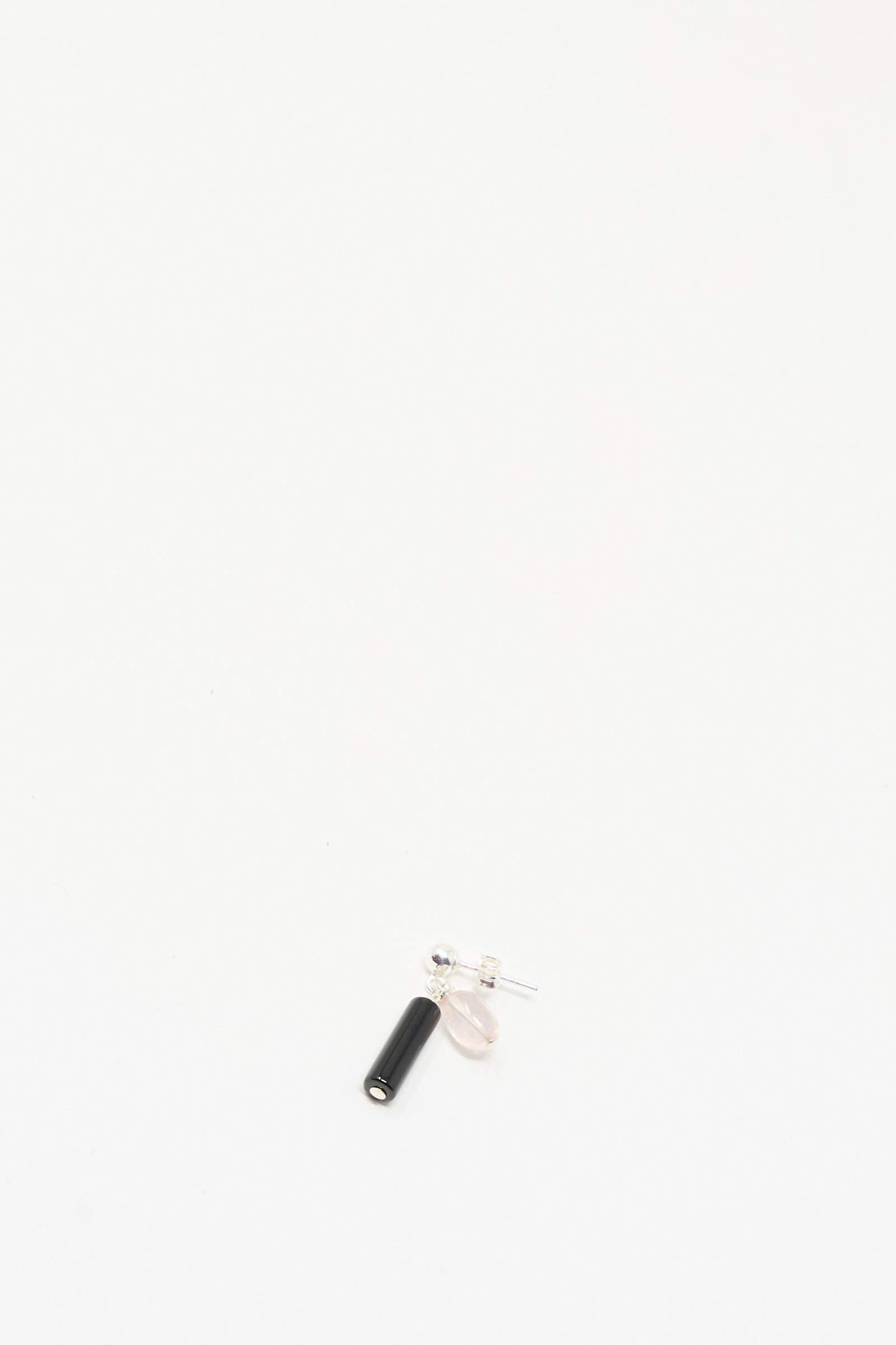 The Santangelo Bebecita Single Earring in Rose Quartz Onyx Drop is a small stud earring with a sterling silver post, featuring a black onyx cylinder and pale pink oval bead, shown on a plain white background.