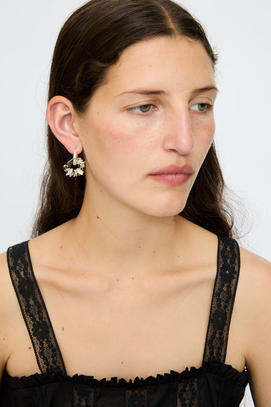 A woman with long brown hair wears a black lace top and Santangelo’s Che Bomba Earrings in Abalone Hoop, featuring sterling silver hardware, as she looks slightly to the side against a plain background.