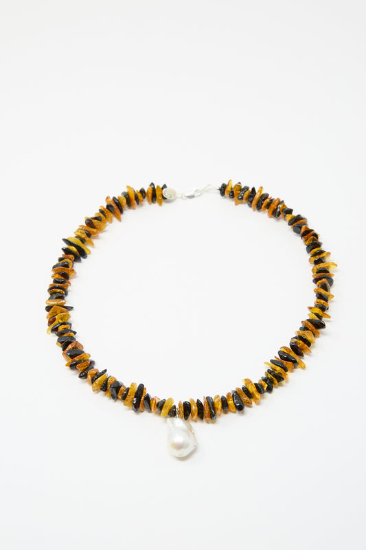 The Santangelo Kitano Necklace in Honey Stripe features alternating Baltic amber and black beads, centered with a bold freshwater pearl teardrop pendant.