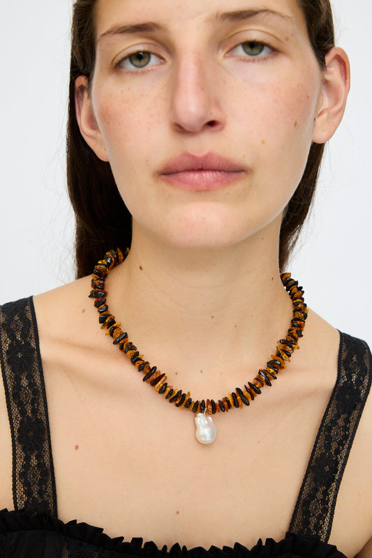 A woman wearing a black lace top and the Santangelo Kitano Necklace in Honey Stripe, looking directly at the camera.