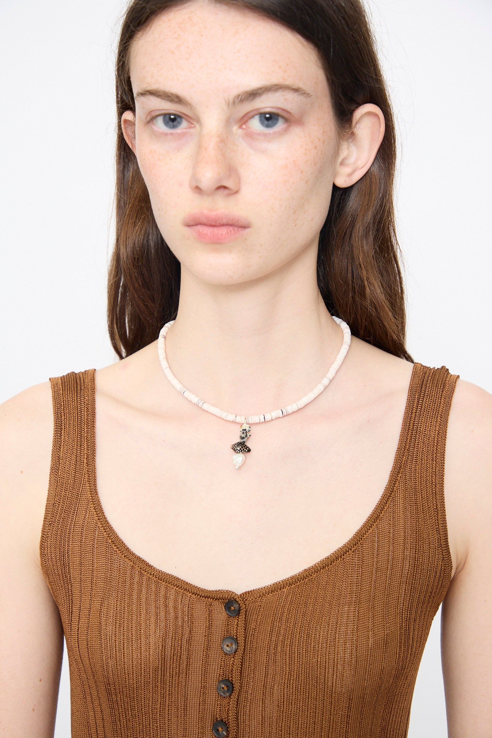 A woman with long brown hair wears Santangelo's Pronto Necklace in Heishi Dalmatian Stack and a sleeveless ribbed brown top, posing against a plain light background.