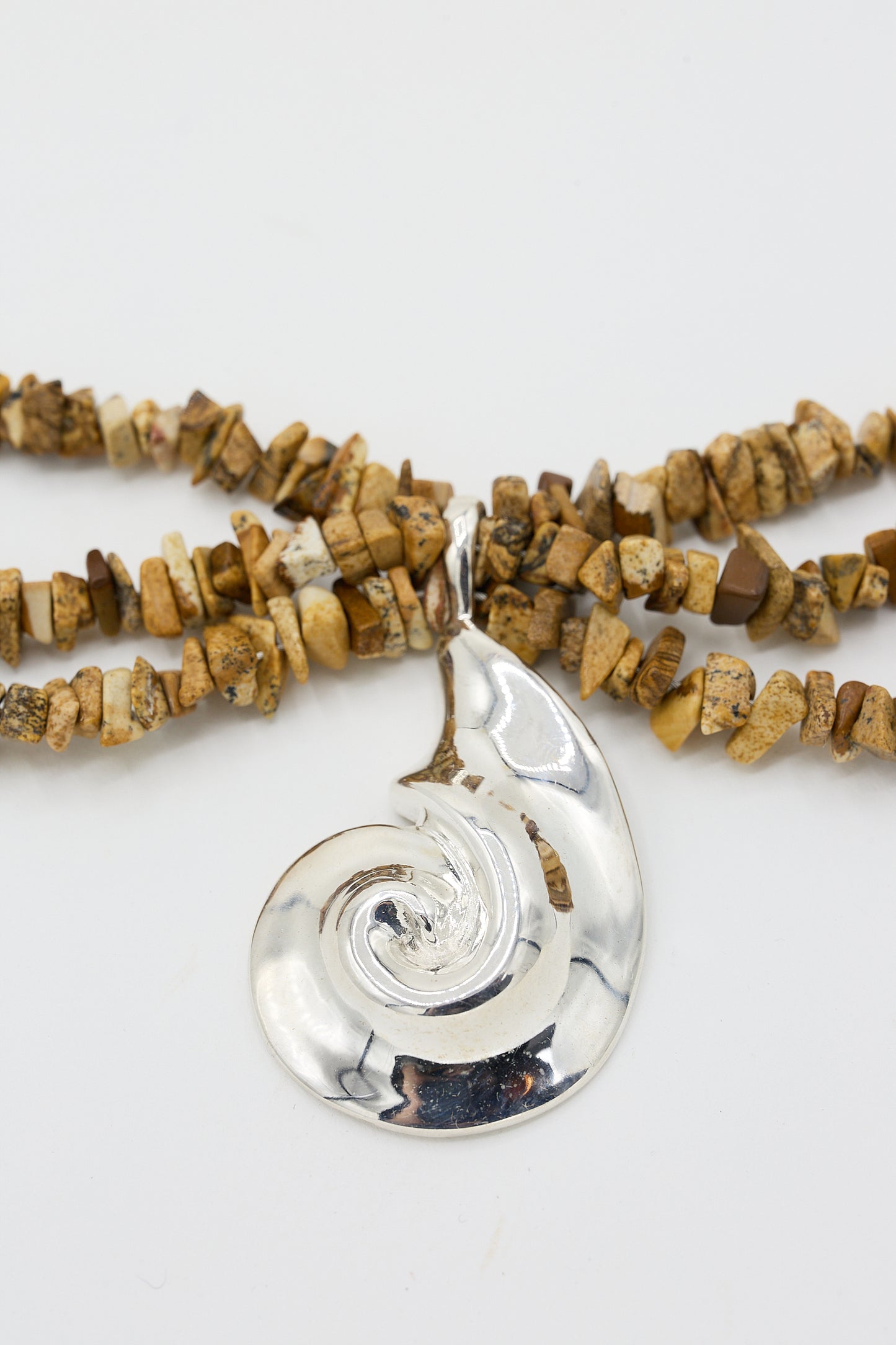 A Cata bracelet in Sand Jasper by Santangelo with a sterling silver pendant and beads made from small pieces of wood on a white background.