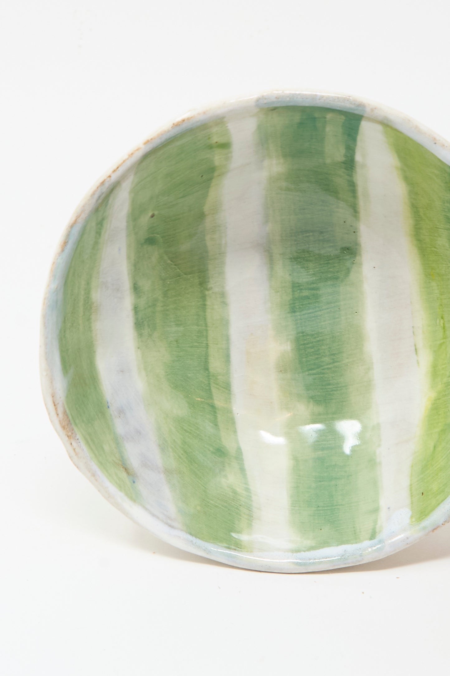 The Bowl in Green and White Stripes by Shino Takeda is a handmade ceramic piece from New York, finished with a glossy glaze and featuring vertical green and white streaks inside.