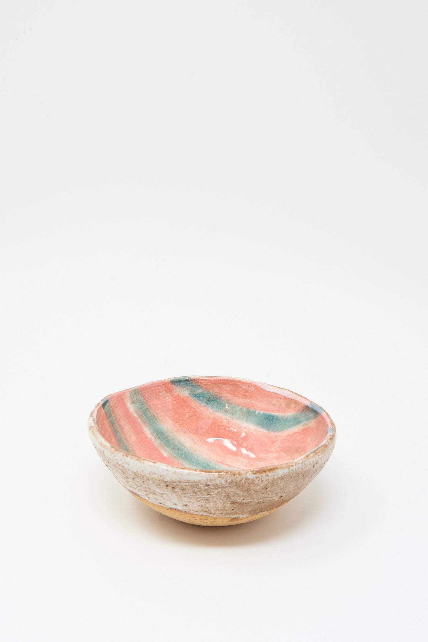 The Bowl in Green Stripe by Shino Takeda is a ceramic piece made in New York, with a rough beige exterior and a glazed interior adorned with pink, green, and orange wavy stripes. The bowl is shown against a plain white background.